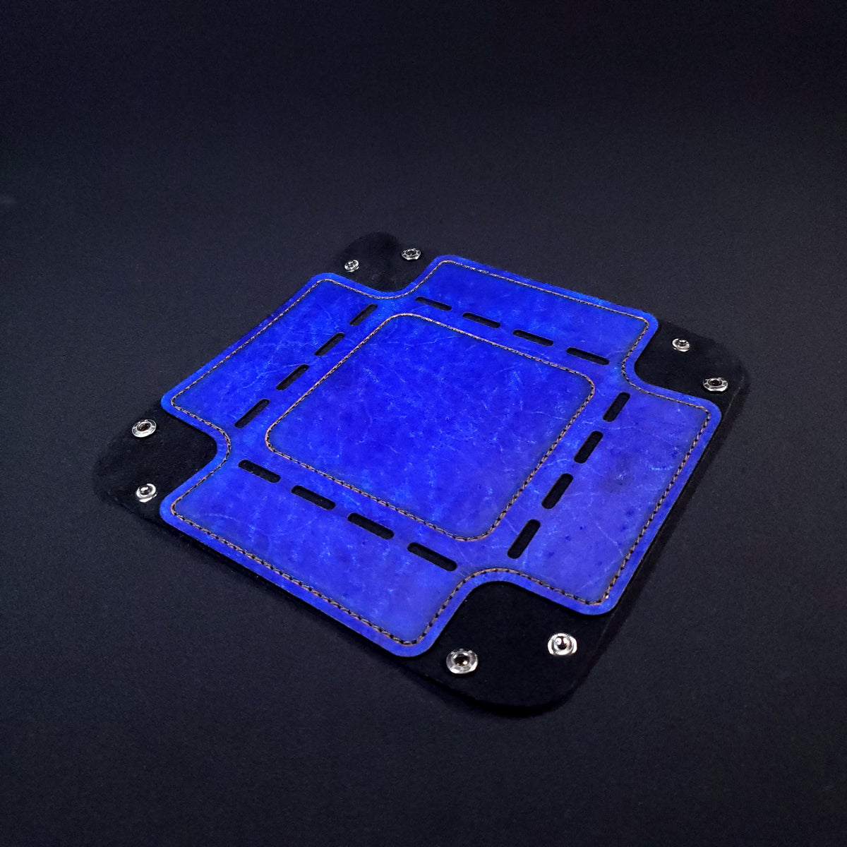 Blue leather dice tray with black stitching and gun-metal buttons, opened and laid flat.