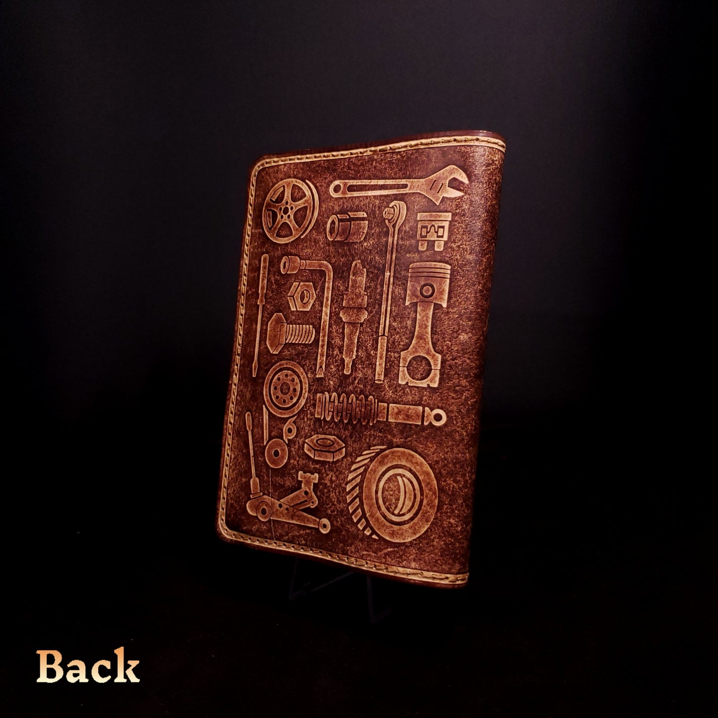 Brown leather notebook cover that's embossed with graphics of mechanic tools.