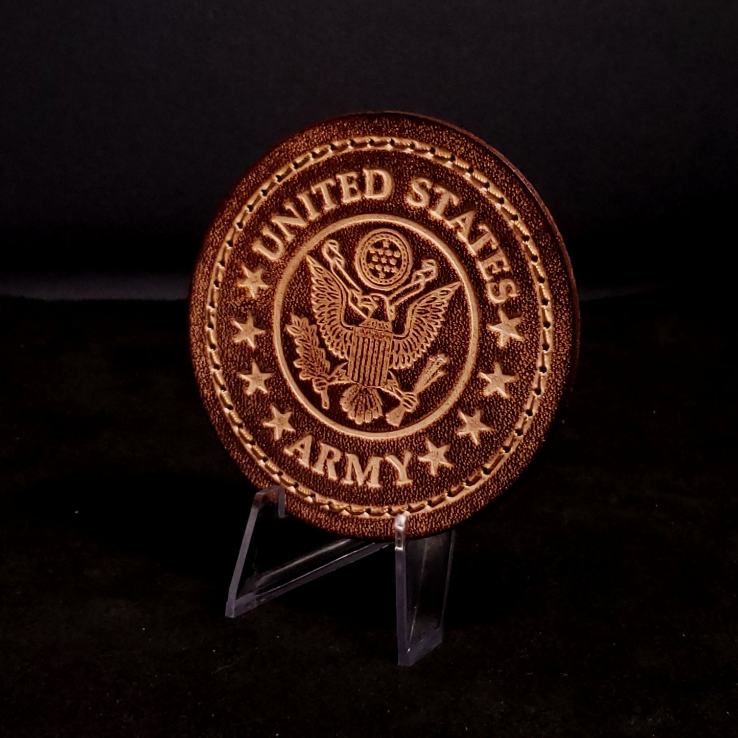 Brown leather velcro patch embossed with text and the united states army emblem, posed on a black background.