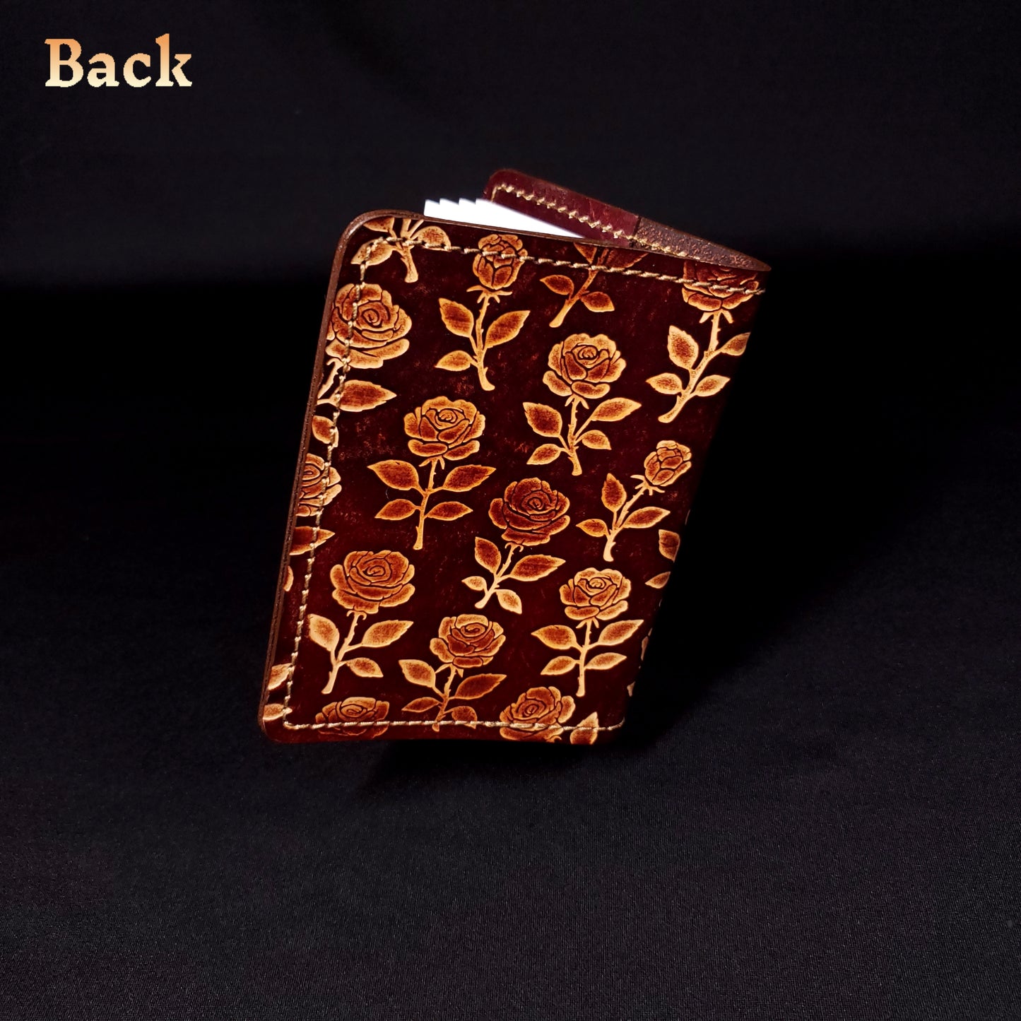 Brown leather mini-composition cover that's embossed with a floral rose pattern, closed and viewed from the back.