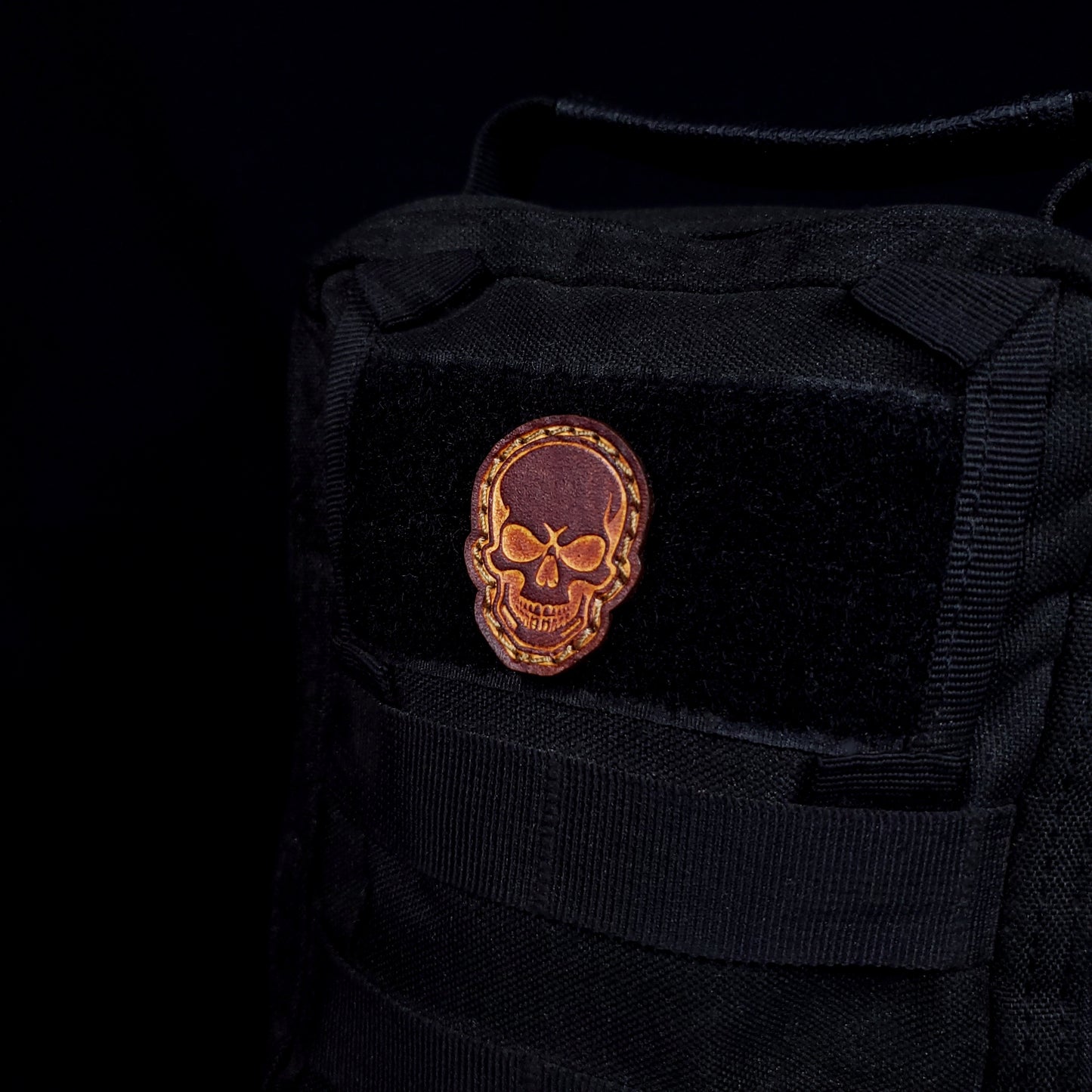 Small leather velcro patch embossed with a skull, affixed to a bag.
