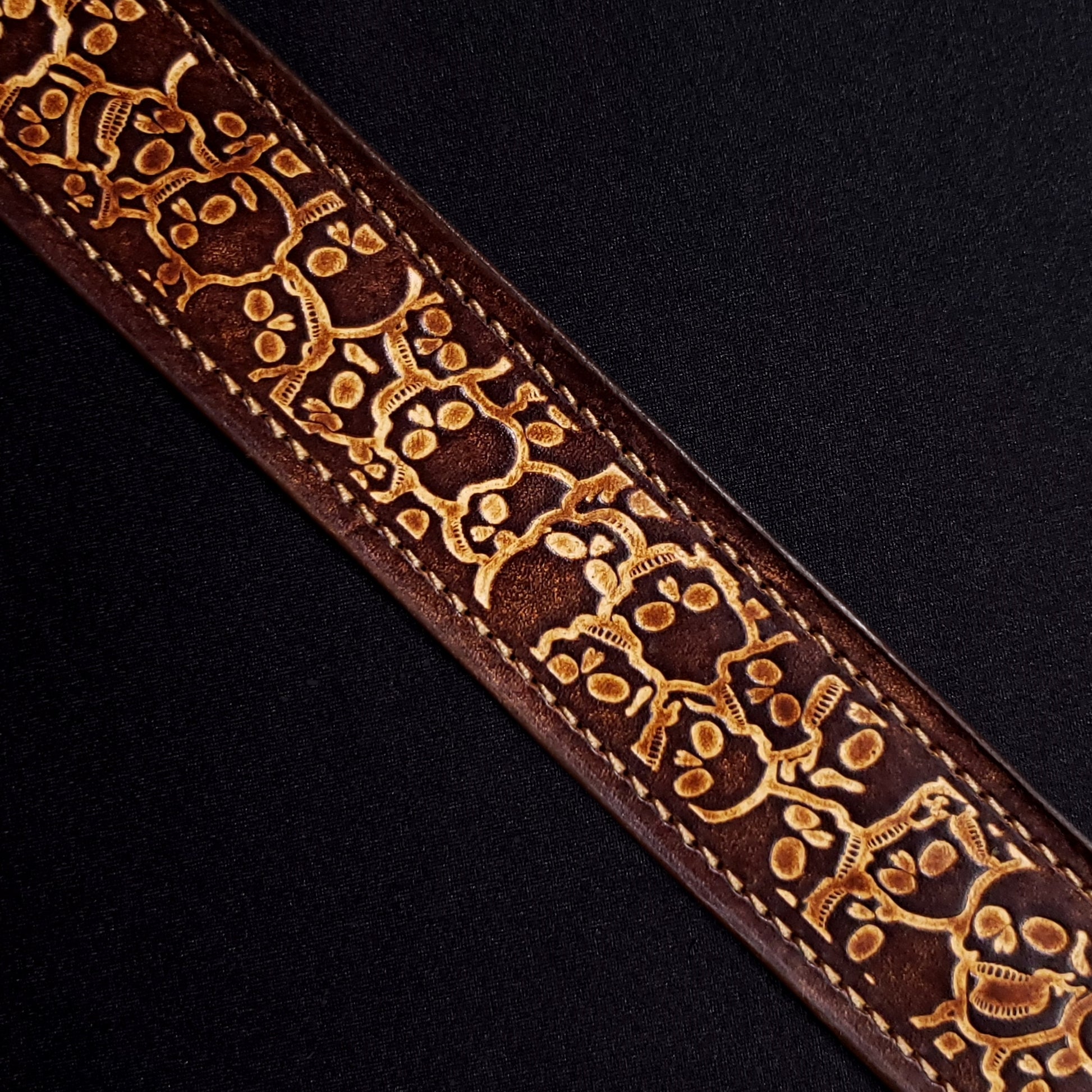 Brown leather belt strap with consistent stitching and a decorative skull pattern.