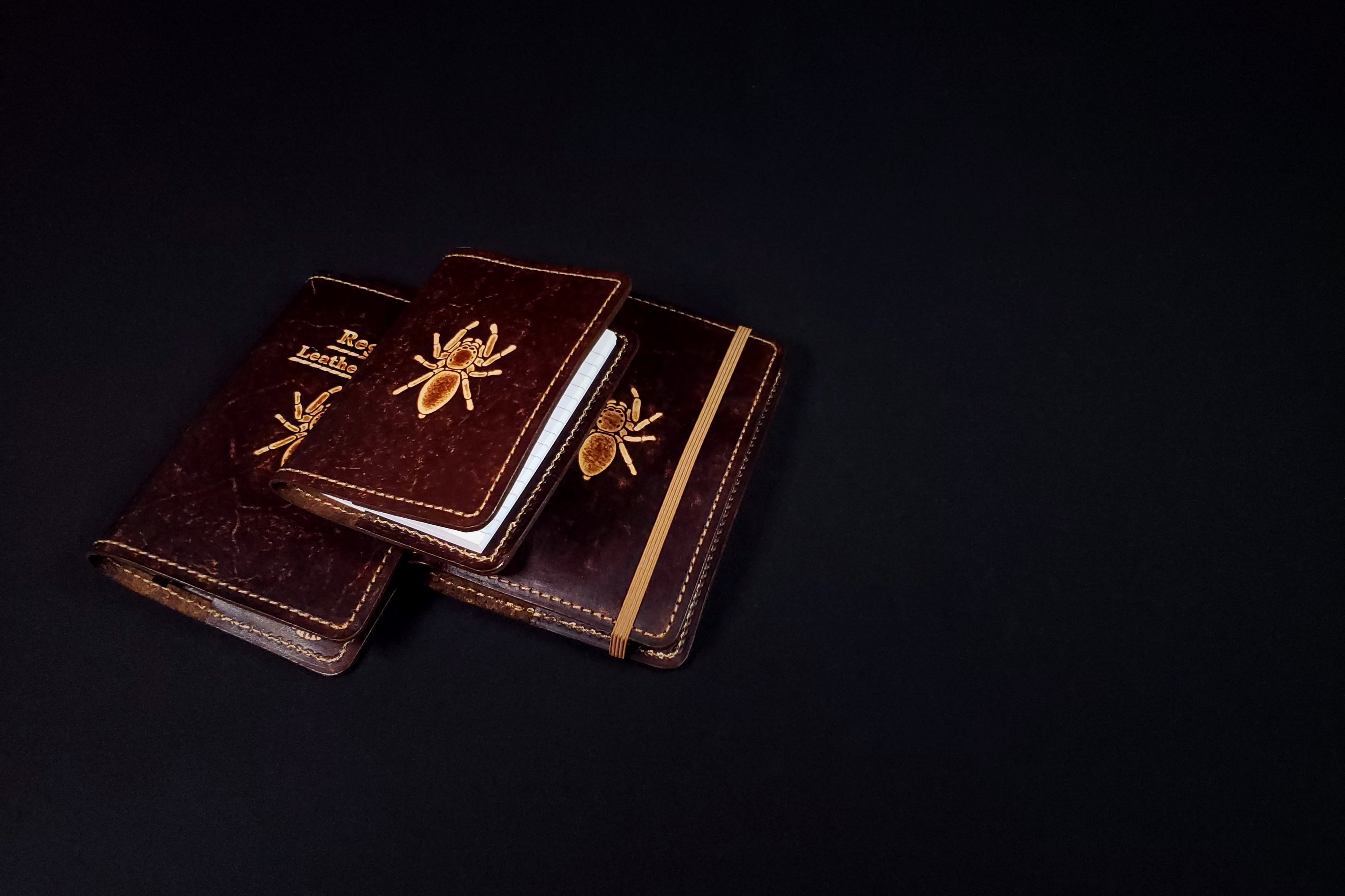 Three leather-bound books with embossed designs on a black background
