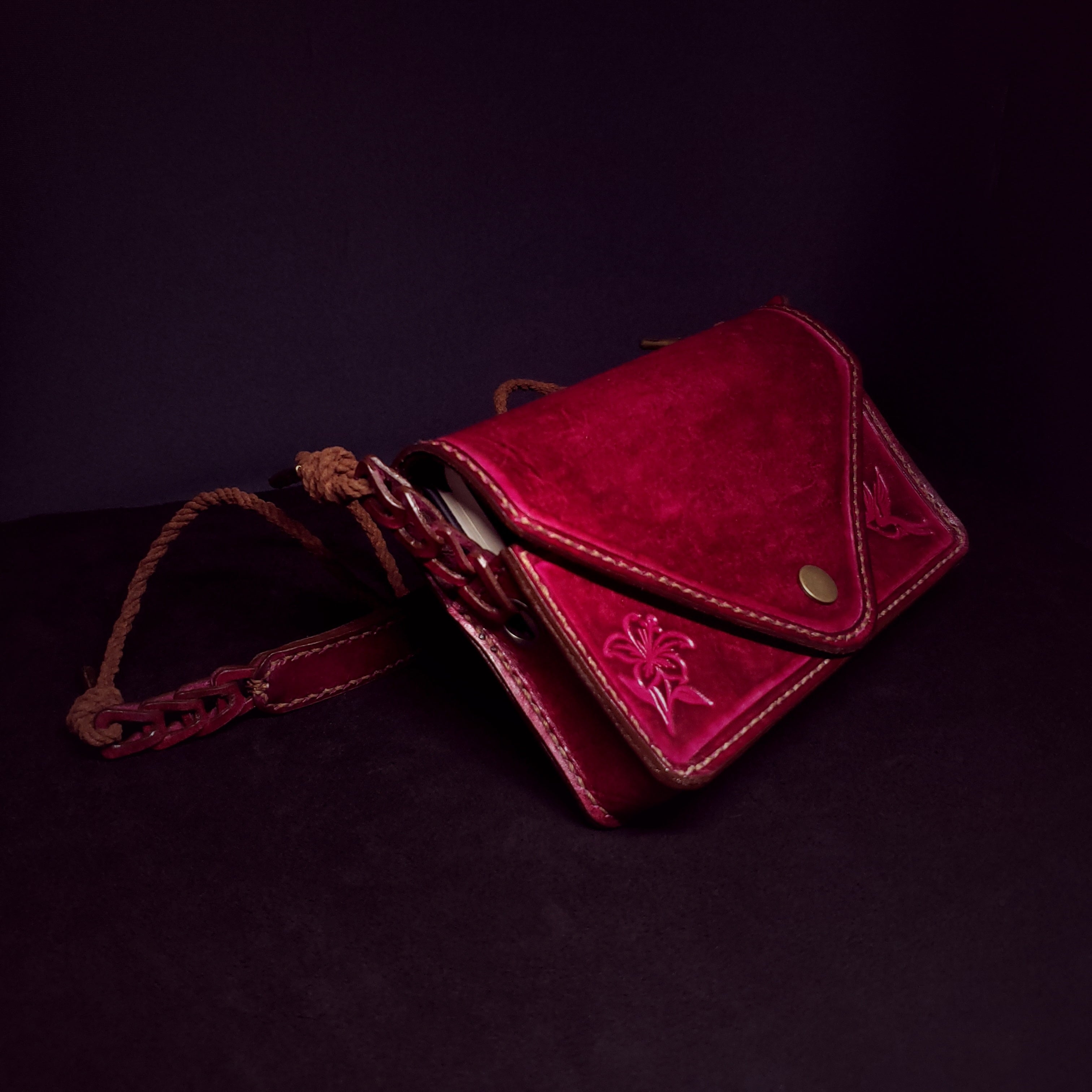 Small pink leather snap purse with a wound lace strap.