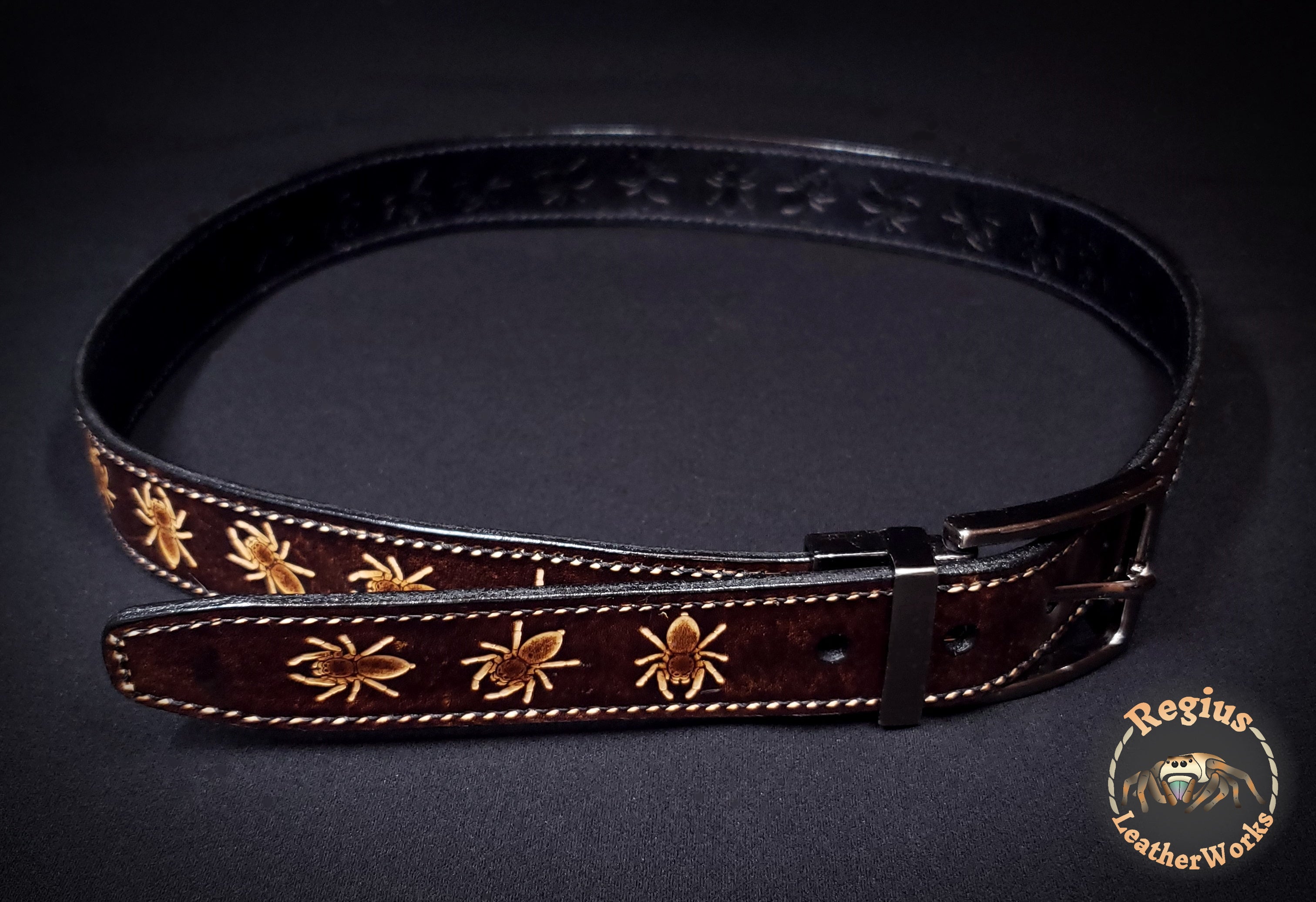 Brown and black reversible belt embossed with a spider pattern.