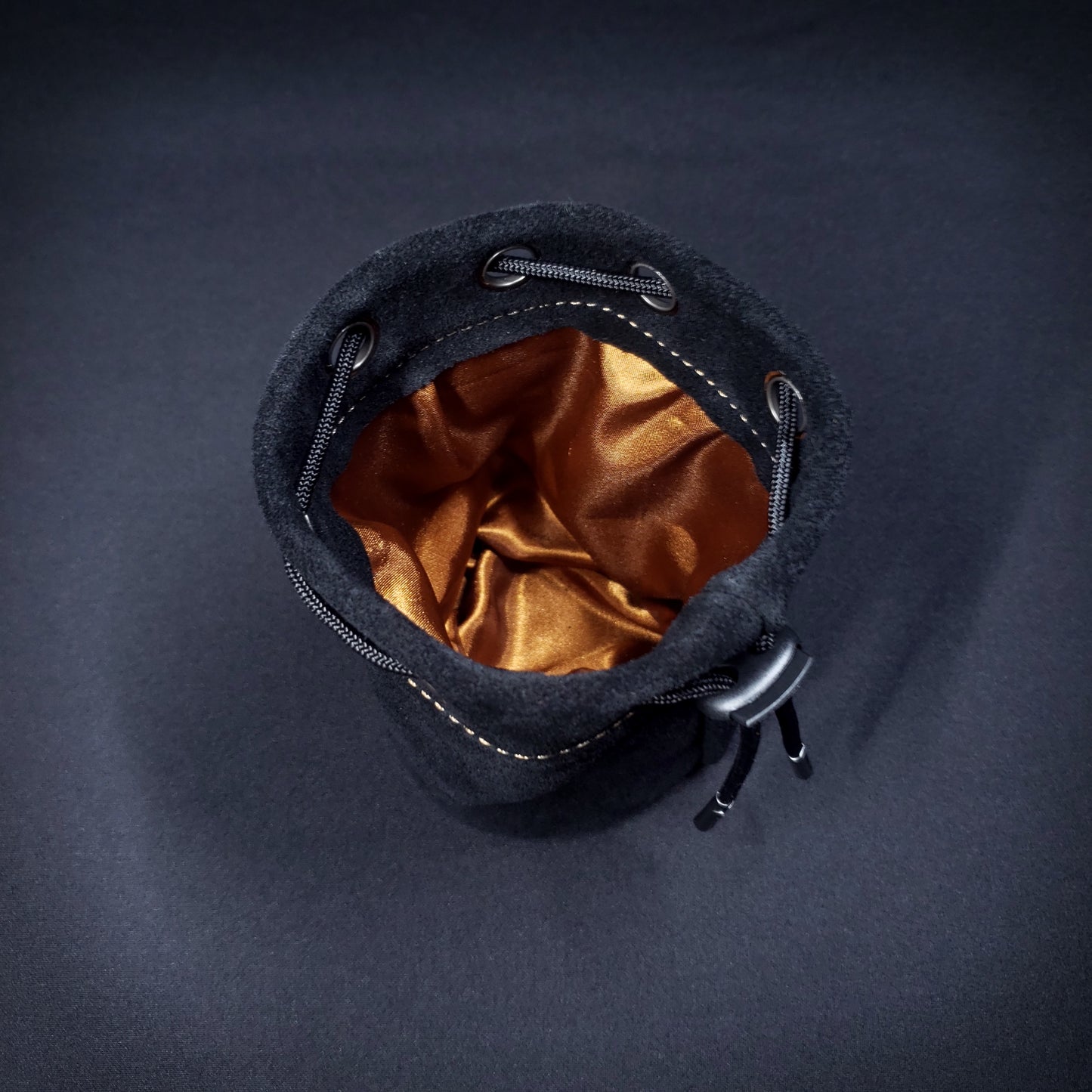 Black suede leather pouch with a black drawstring, looking down into its brown satin interior.