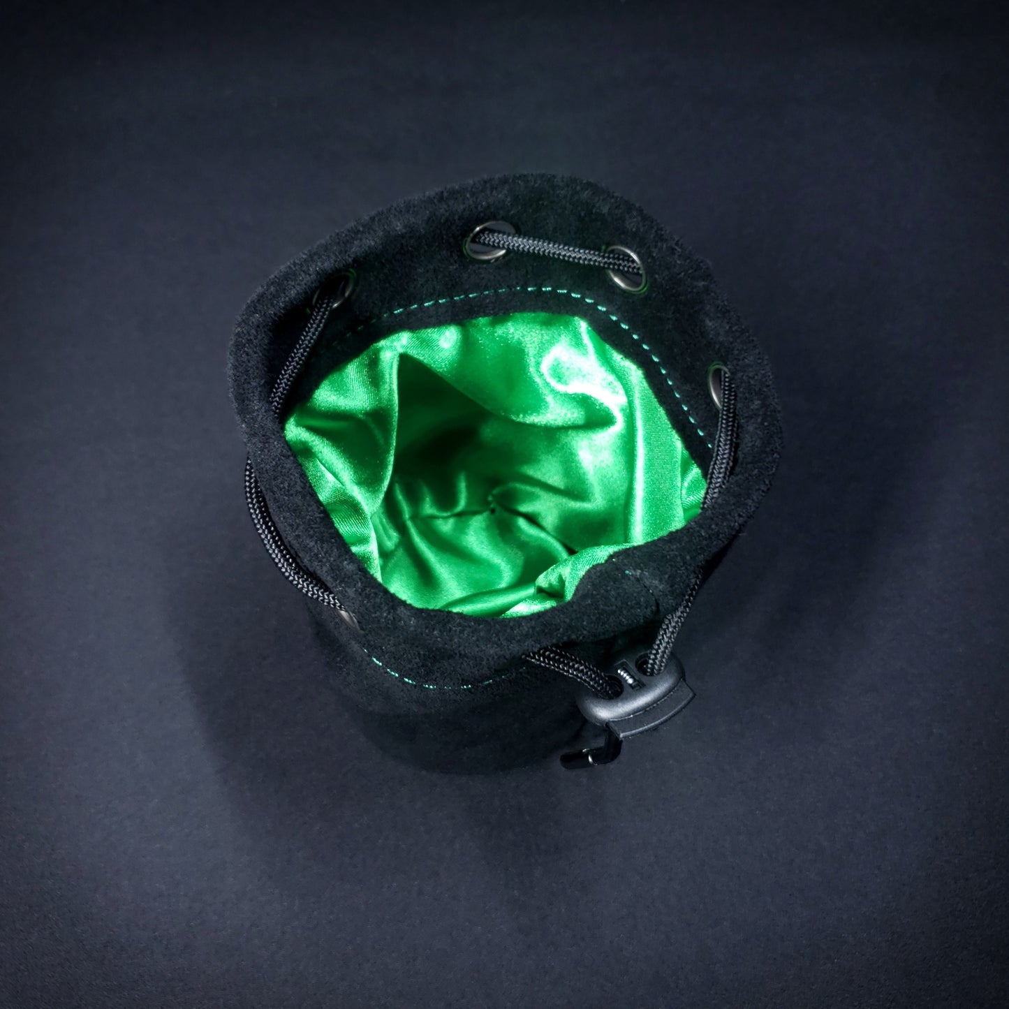 Black suede leather pouch with a black drawstring, looking down into its green satin interior.