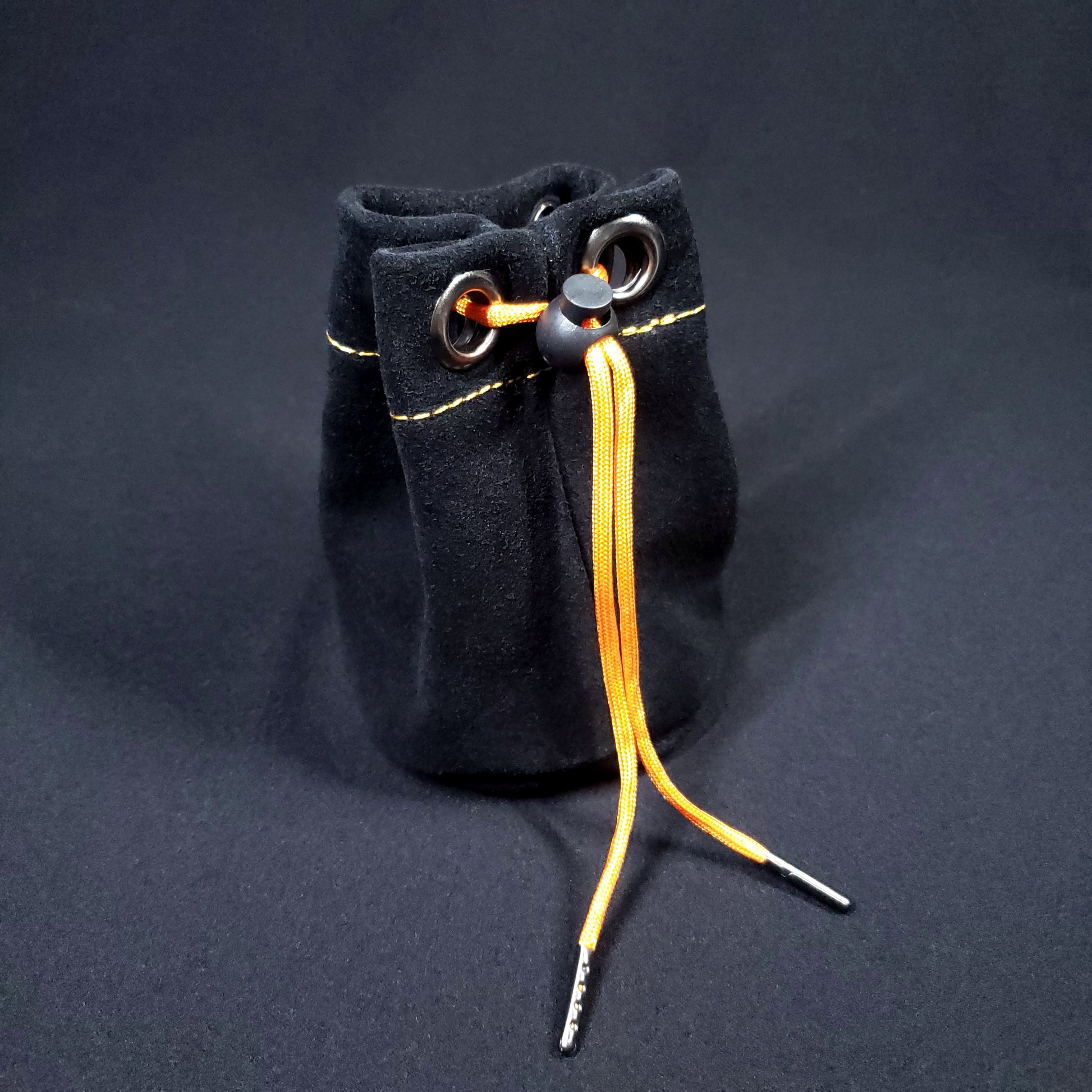 Black suede leather pouch with orange stitching and an orange drawstring, pulled closed.