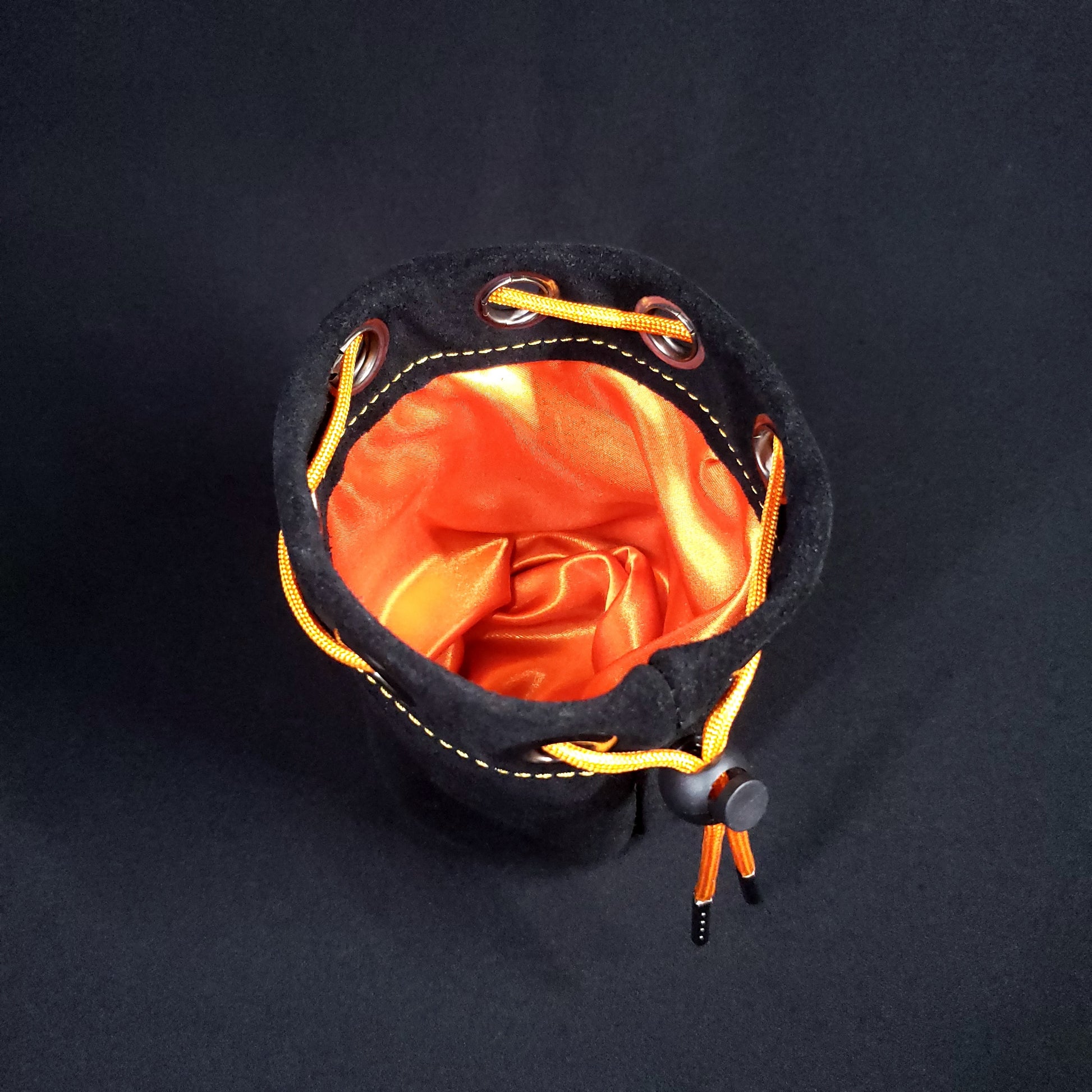 Black suede leather pouch with an orange drawstring, looking down into its orange satin interior.