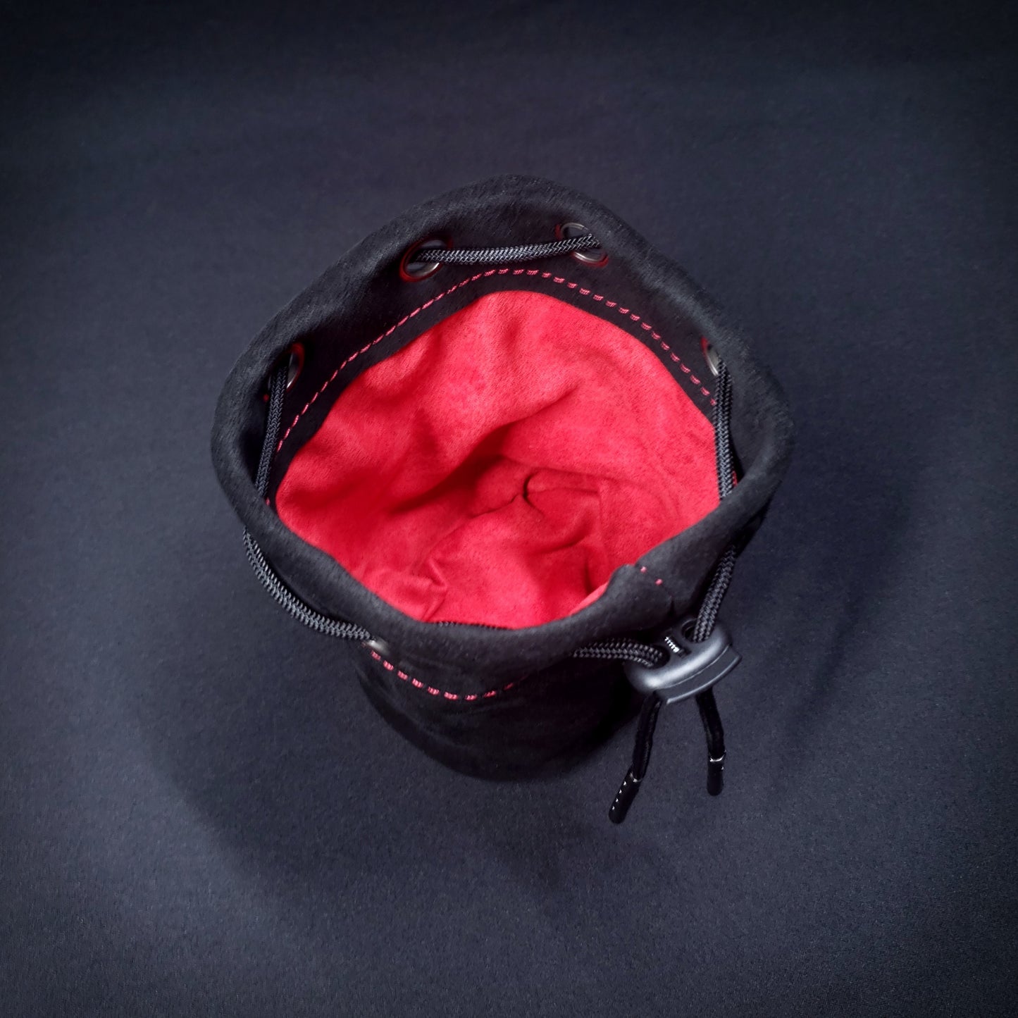 Black suede leather pouch with a black drawstring, looking down into its red cloth interior.