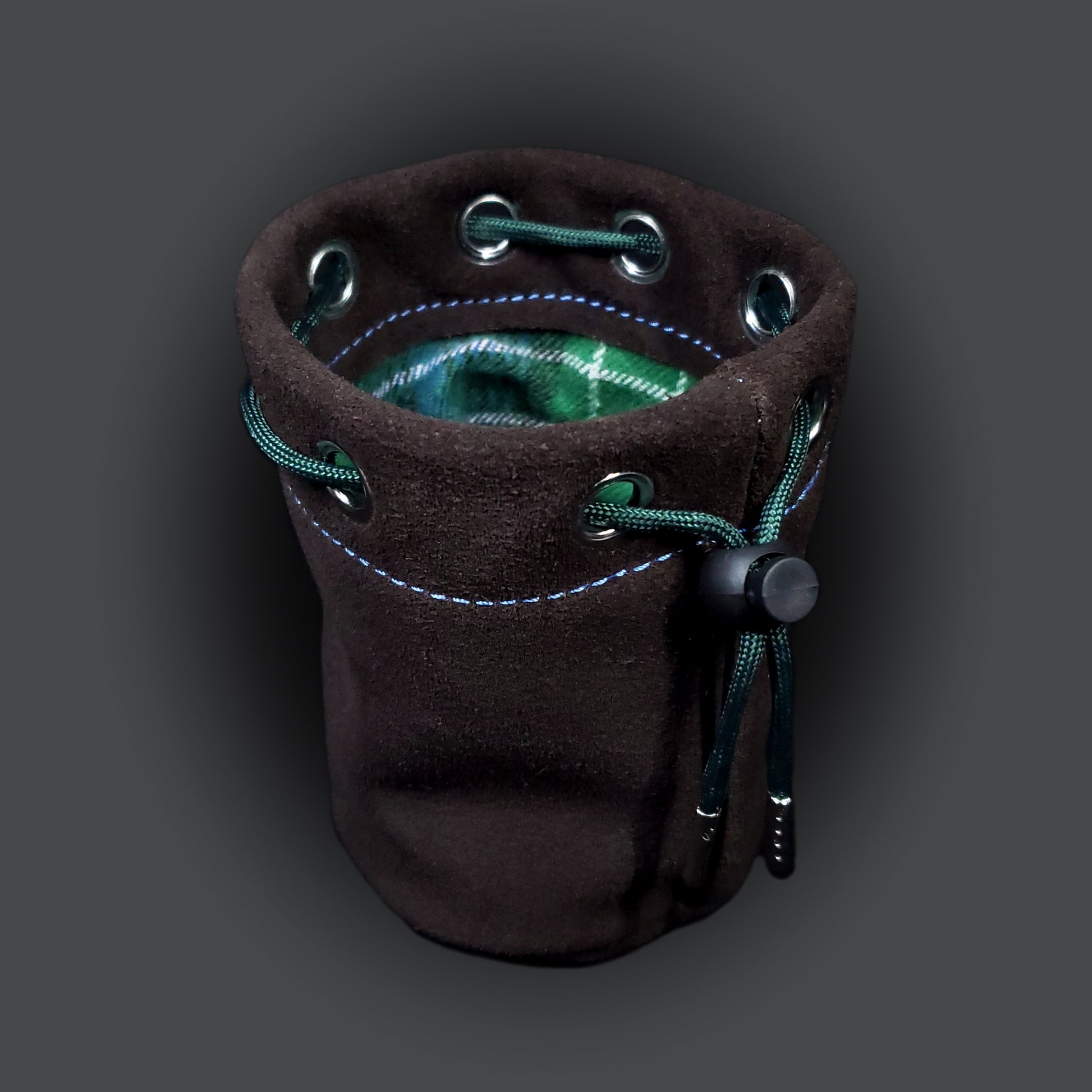 Brown suede leather pouch with a blue and green plaid cloth interior and green drawstring.