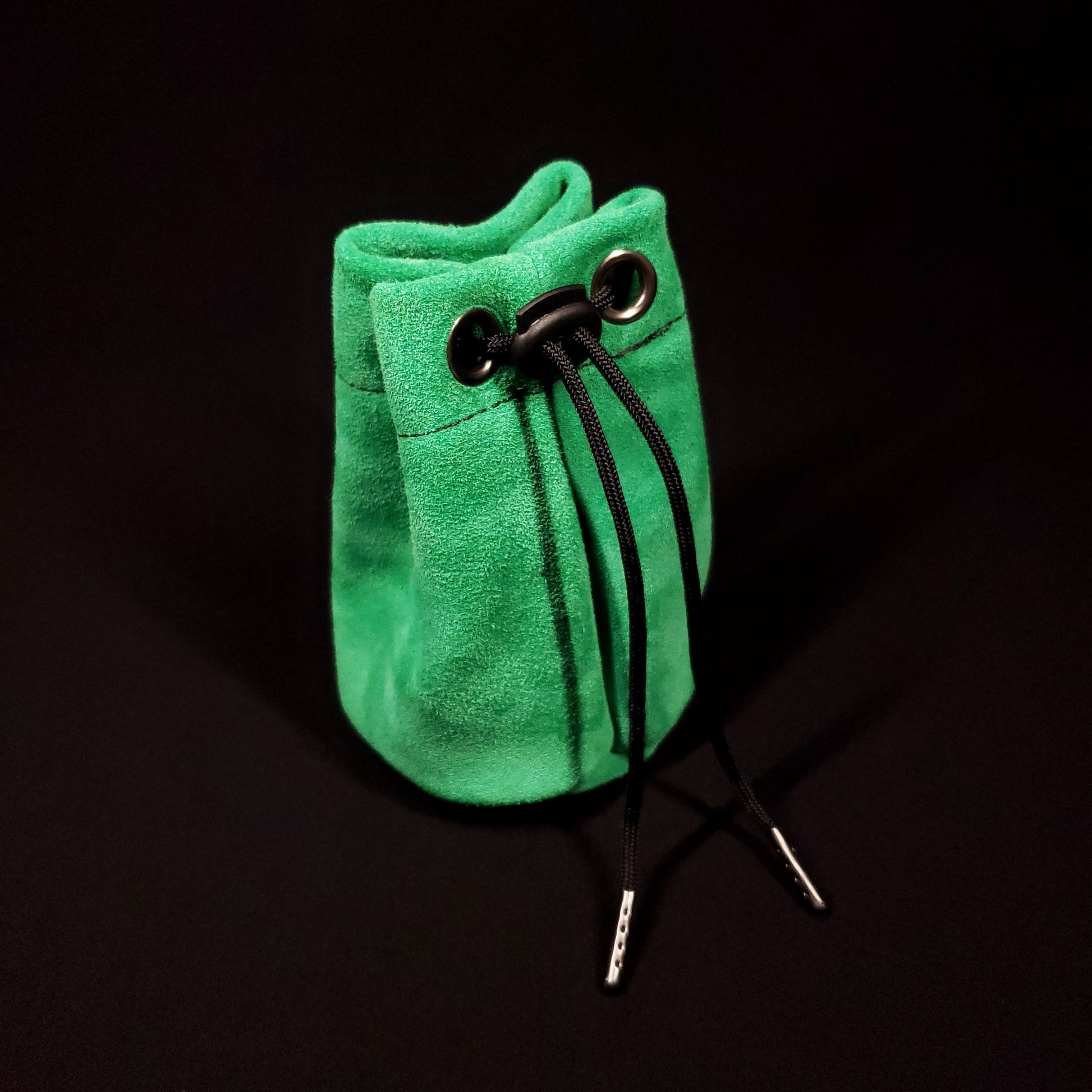 Green suede leather pouch with a black fabric interior and black drawstring, pulled closed.