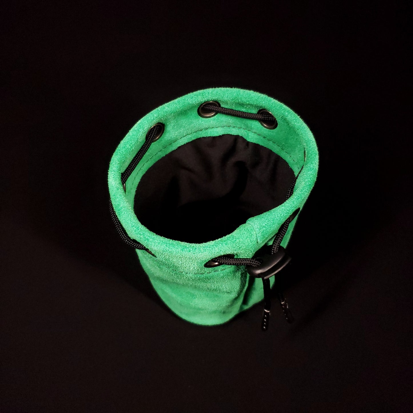 Green suede leather pouch with a black drawstring, looking down into its black fabric interior.