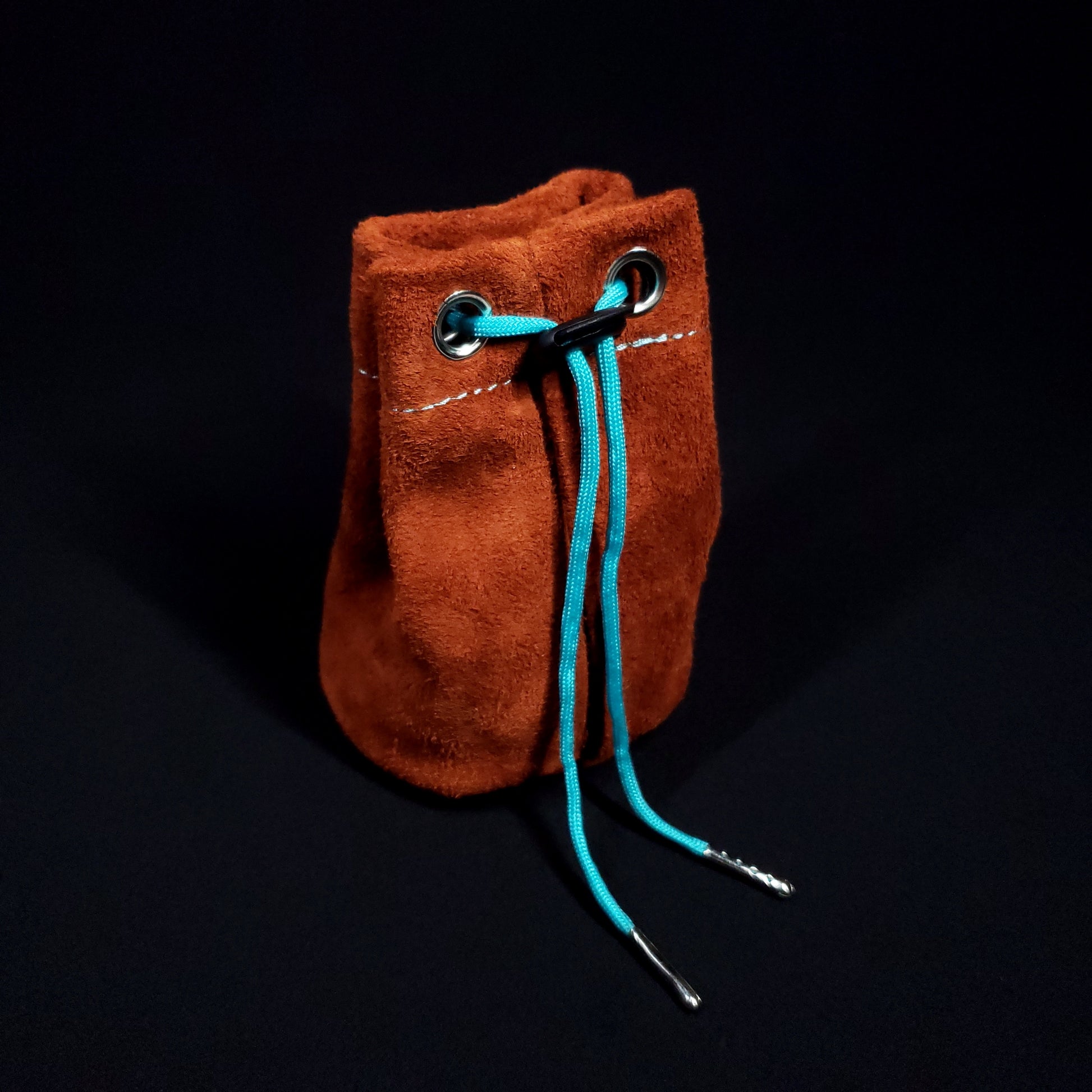 Light brown suede leather pouch with a light blue cloth interior and light blue drawstring, pulled closed.