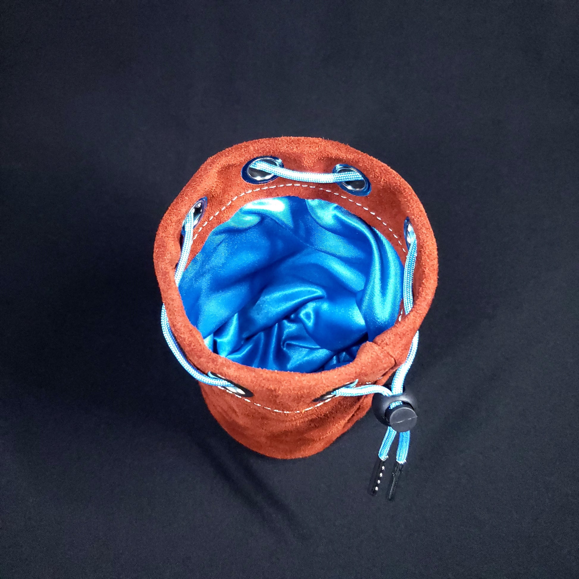 Rust colored suede leather pouch with a light blue drawstring, looking down into its light blue satin interior.