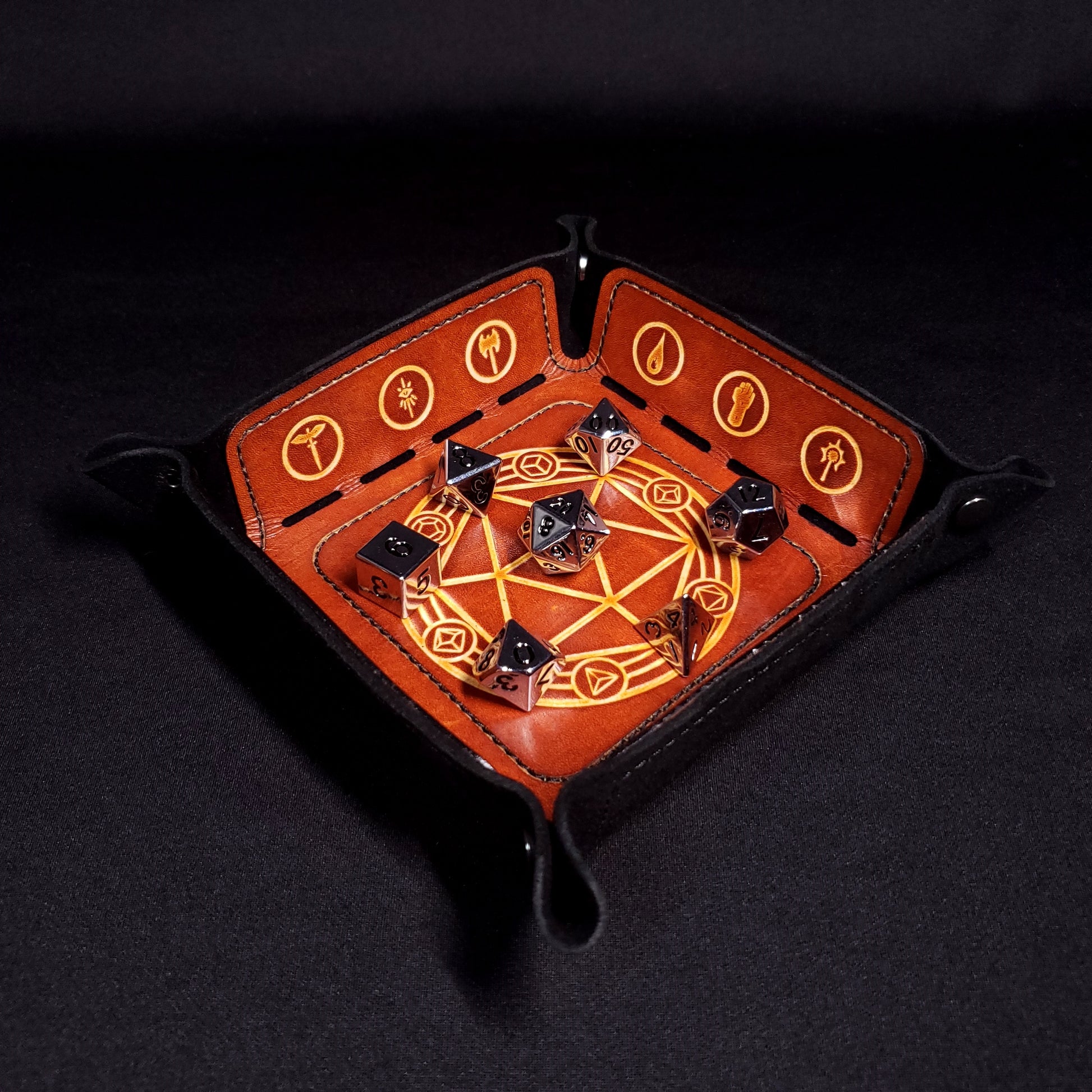 Black and brown leather dice tray decorated with dungeons and dragons icons with seven dice.