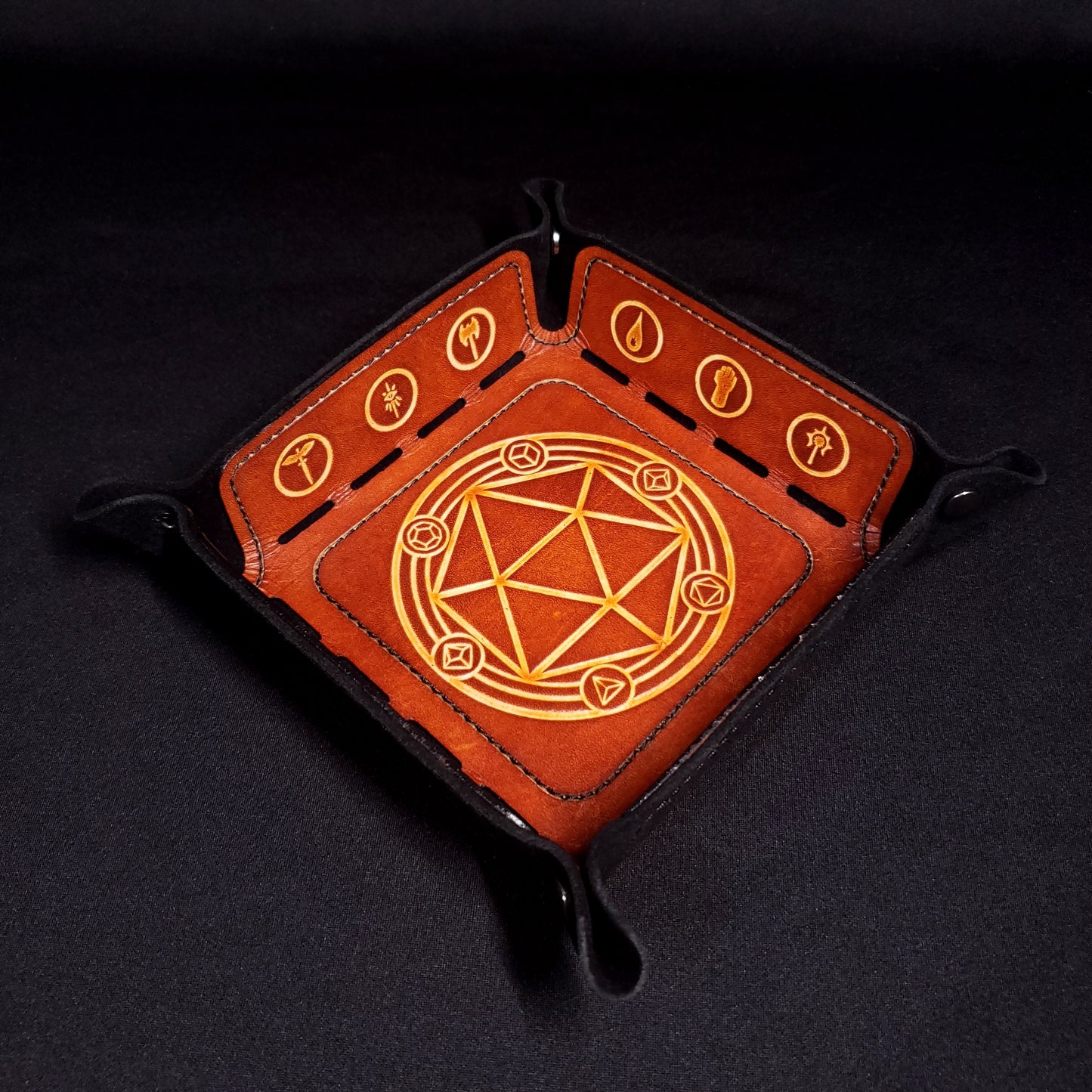 Black and brown leather dice tray decorated with dungeons and dragons icons, viewed from the top.