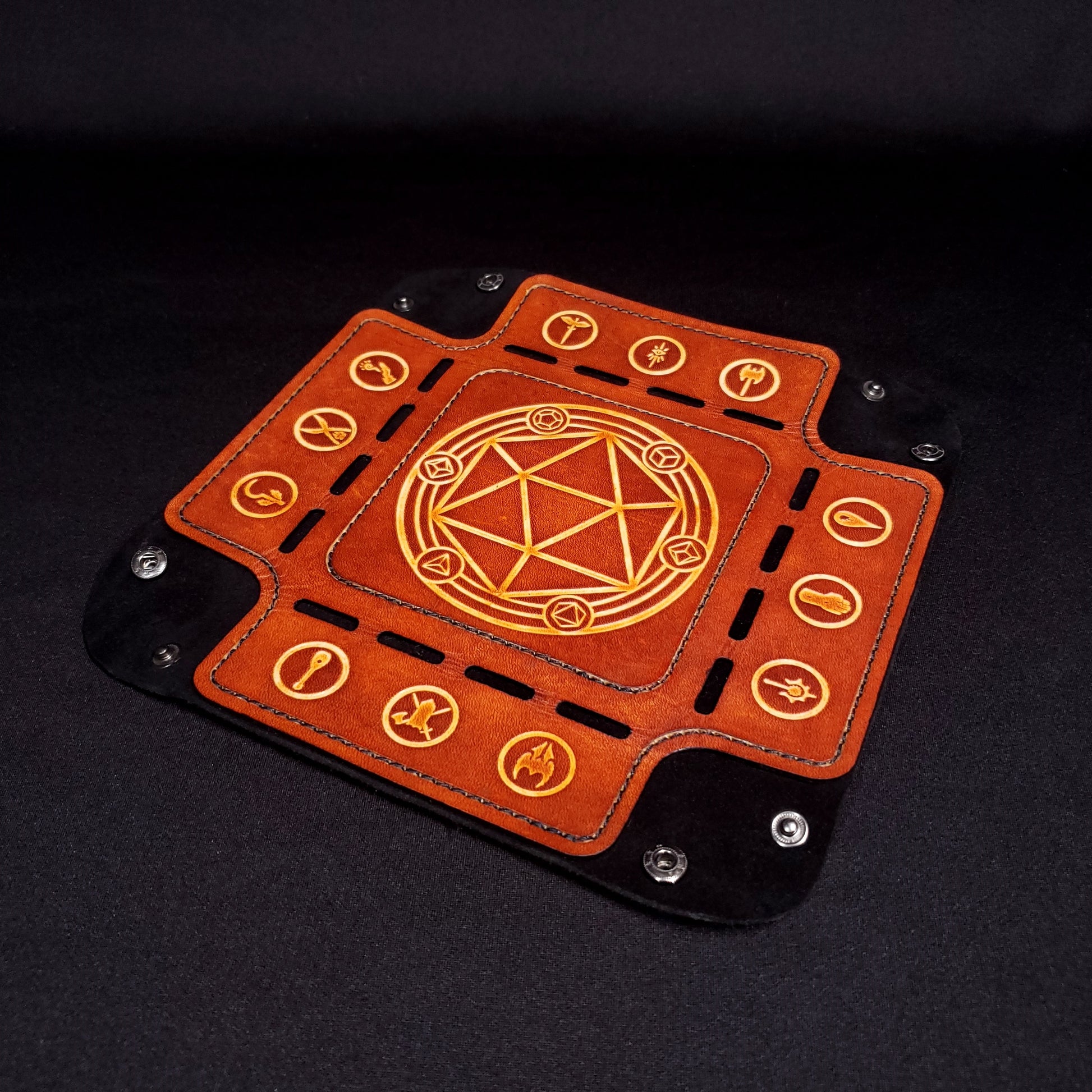 Black and brown leather dice tray decorated with dungeons and dragons icons while opened flat.