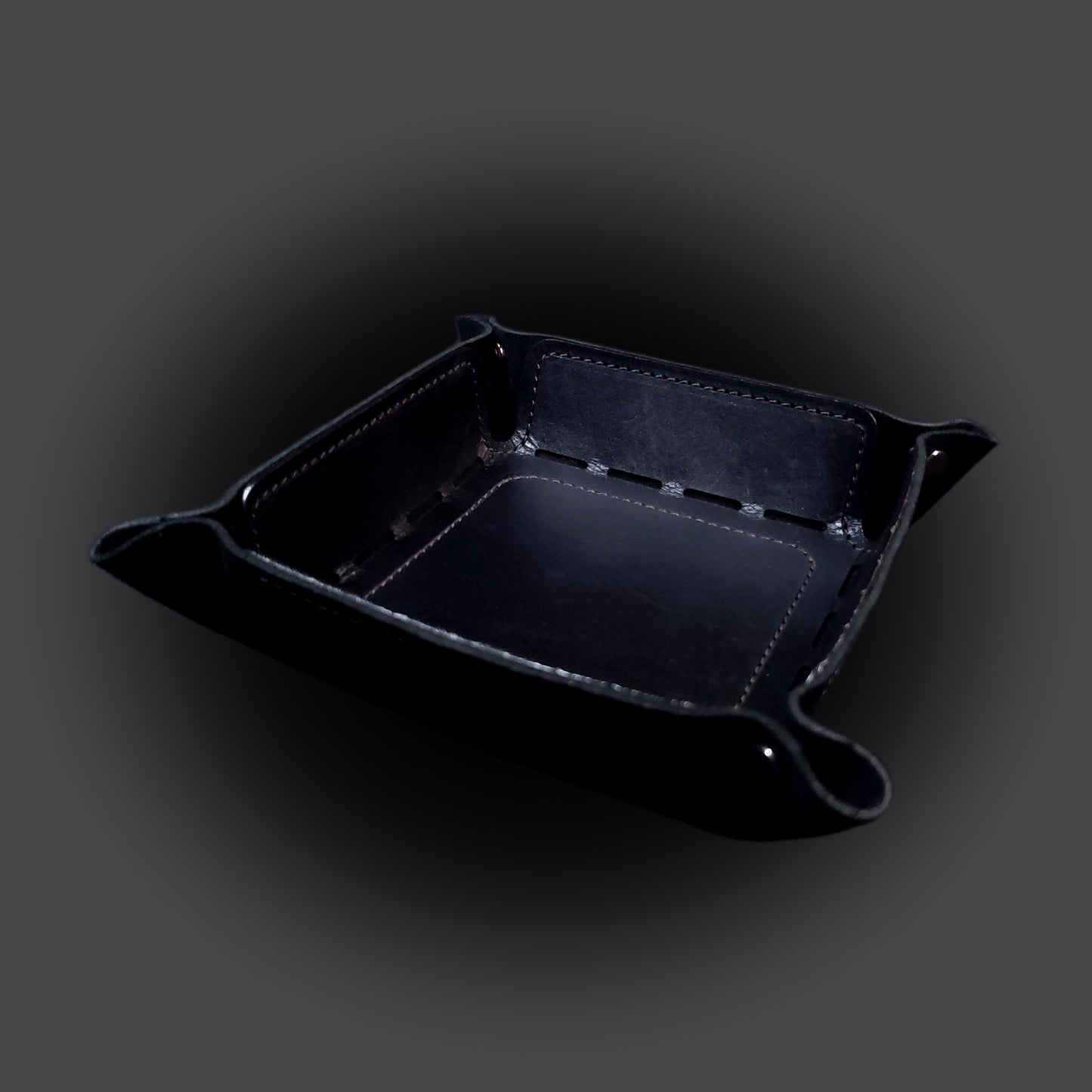 Black leather dice tray with black stitching and gun metal buttons, viewed from the front.