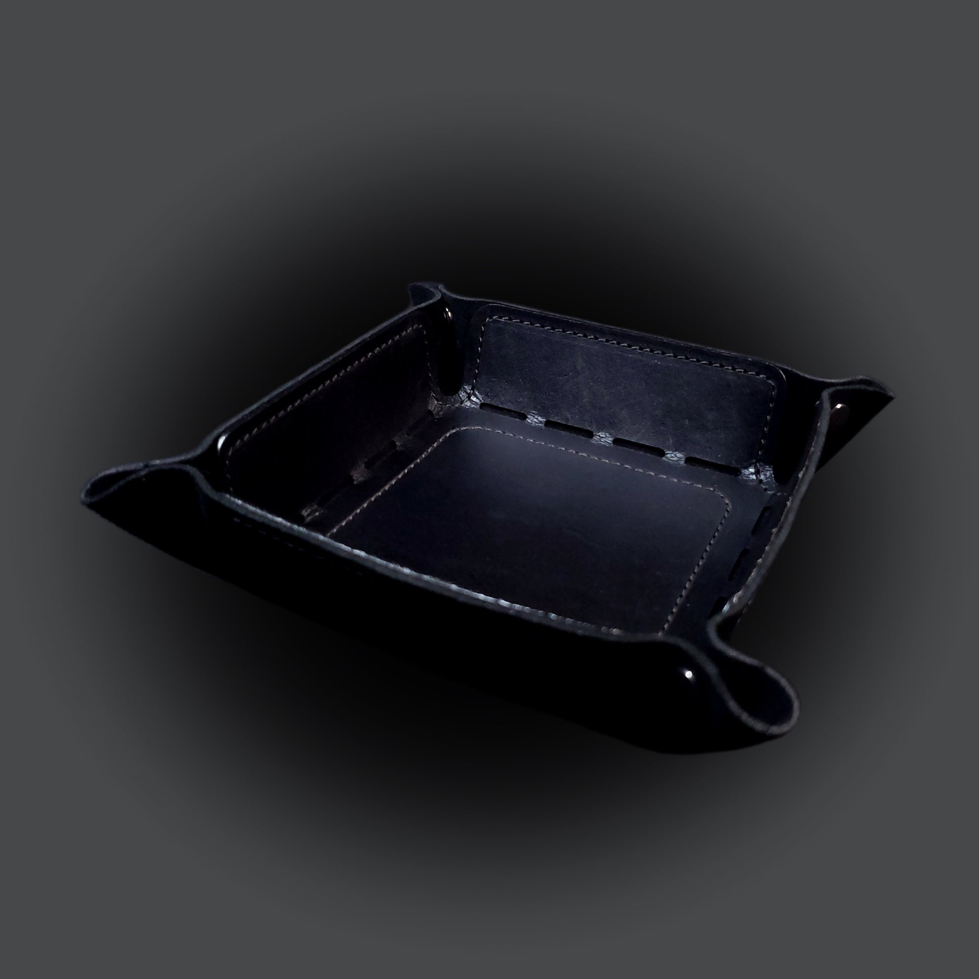 Black leather dice tray with black stitching and gun metal buttons, viewed from the front.