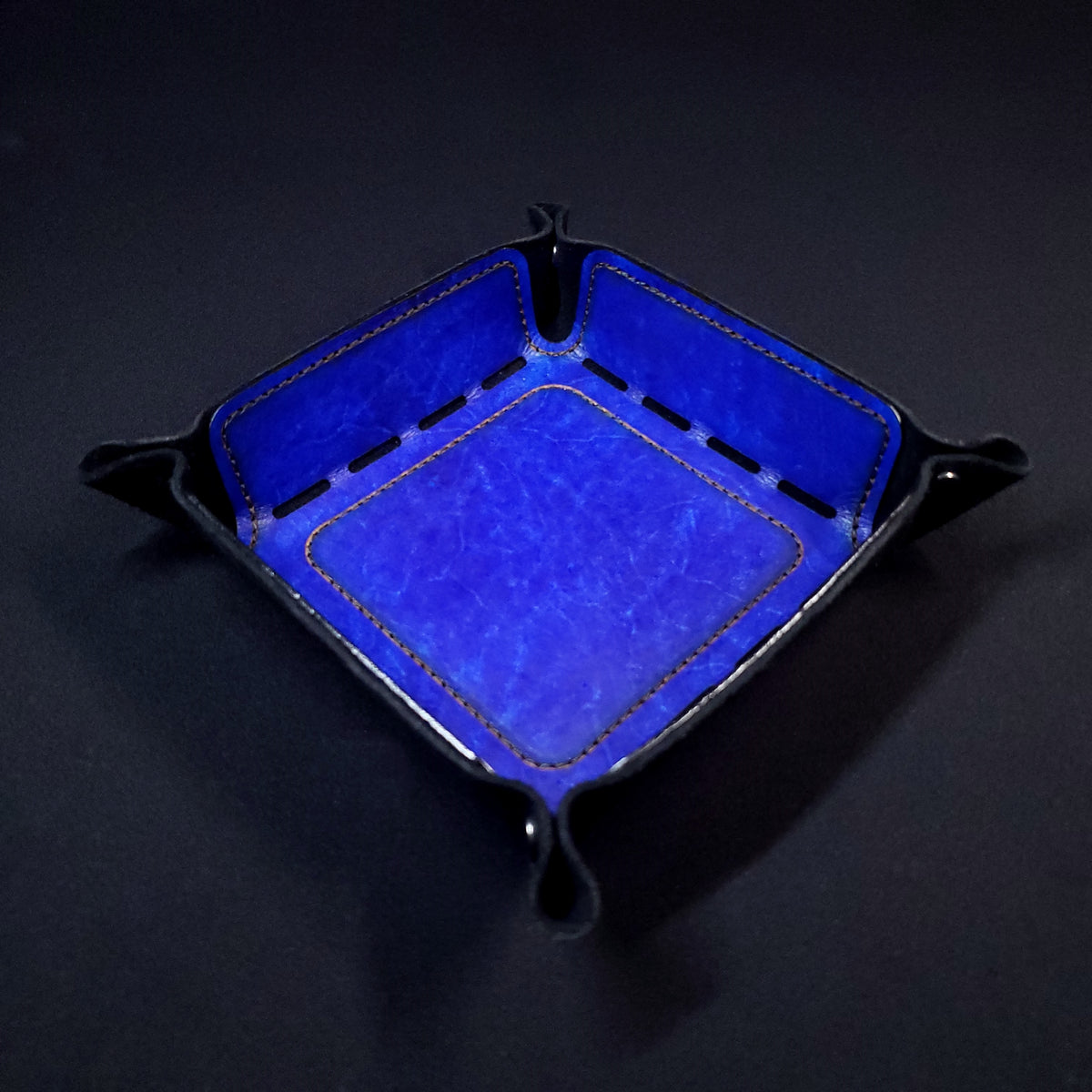 Blue leather dice tray with black stitching and gun metal buttons, viewed from the top.