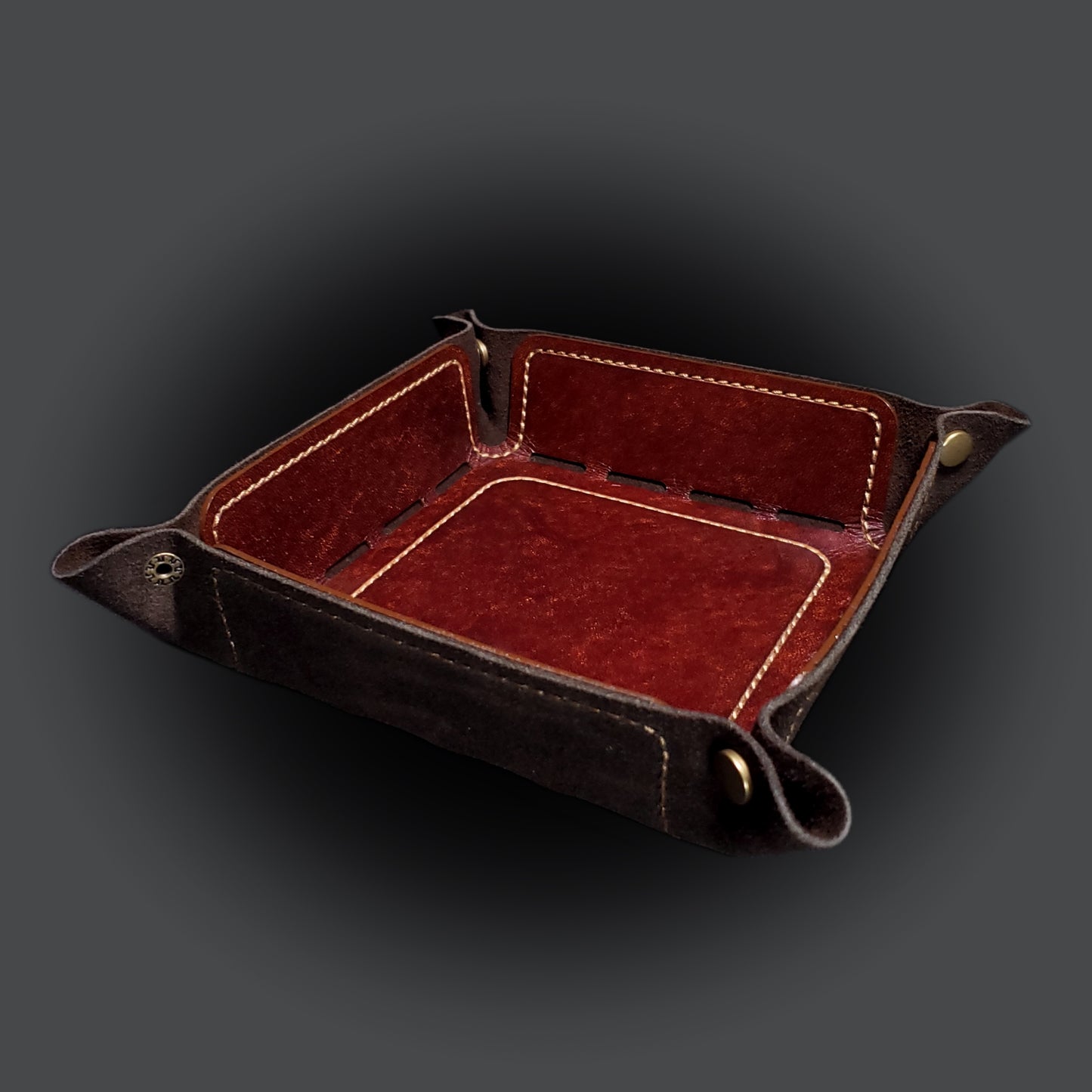 Brown leather dice tray with light brown stitching and bronze buttons, viewed from the front.