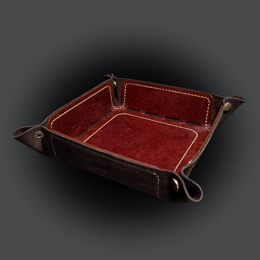 Brown leather dice tray with light brown stitching and bronze buttons, viewed from the front.