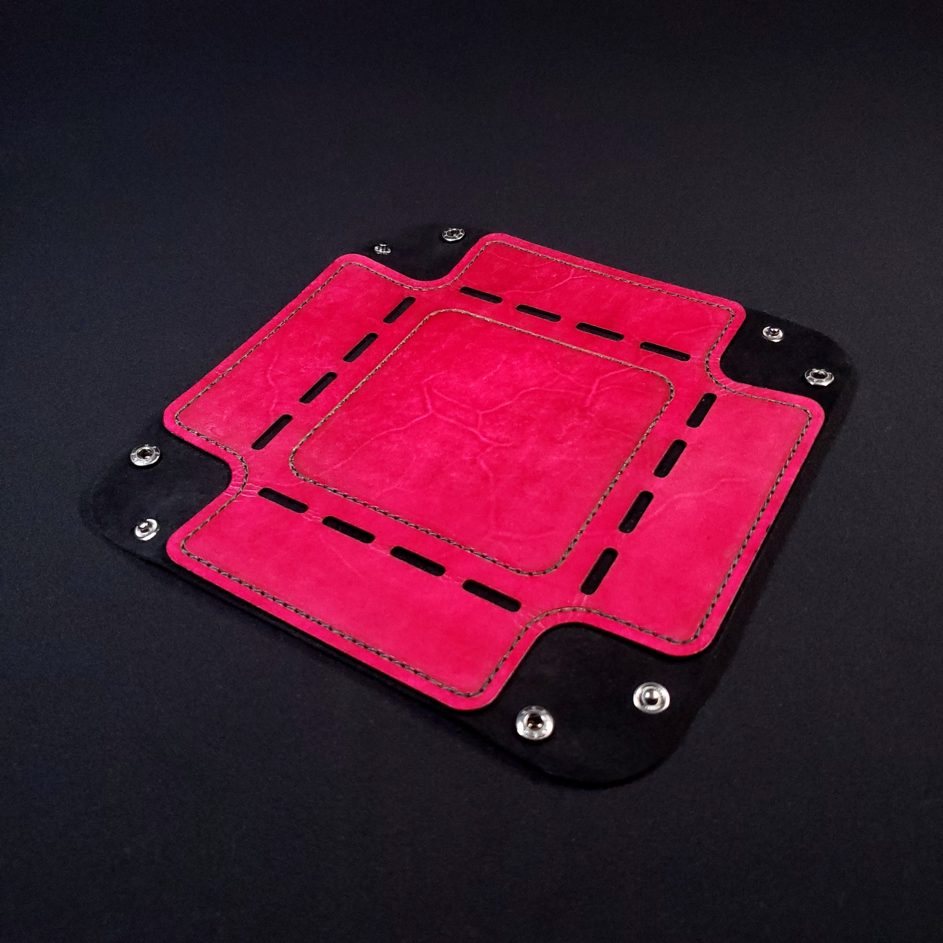 Red leather dice tray with black stitching and gun metal buttons, opened and laid flat.