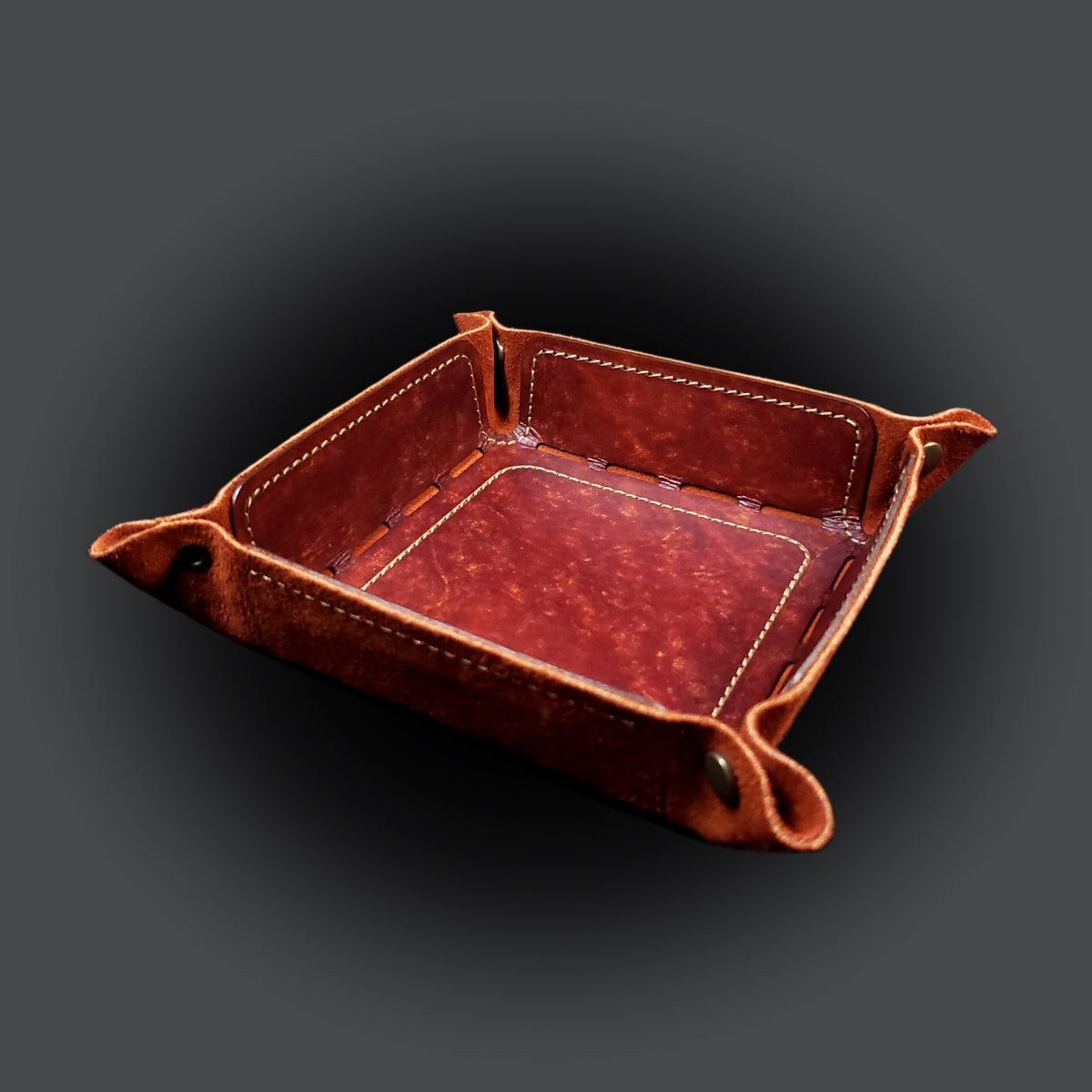 Rust brown leather dice tray with light brown stitching and bronze buttons, viewed from the front.