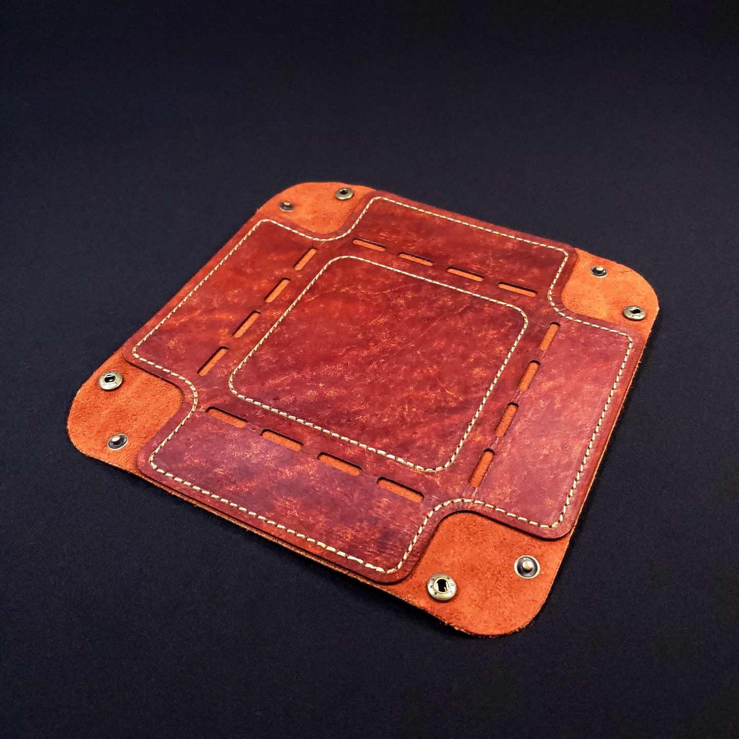 Rust brown leather dice tray with light brown stitching and bronze buttons, opened and laid flat.