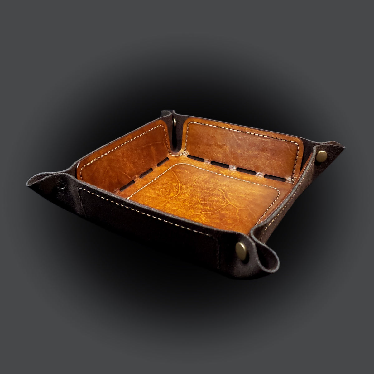 Walnut brown leather dice tray with light brown stitching and bronze buttons, viewed from the front.