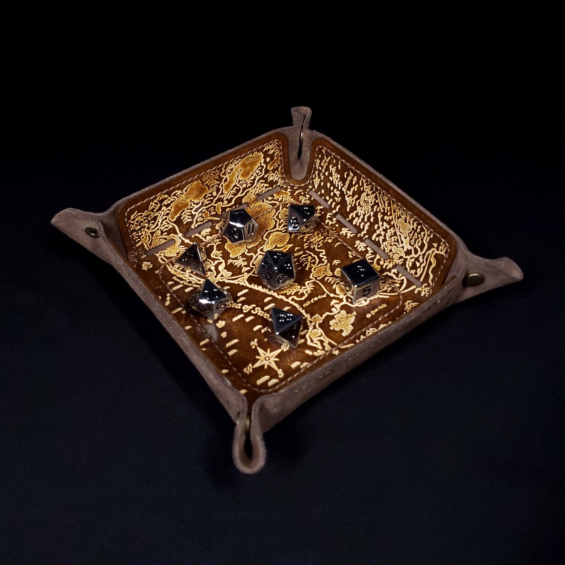 Brown leather dice tray decorated with a fantasy map of the sword coast with seven dice inside it.