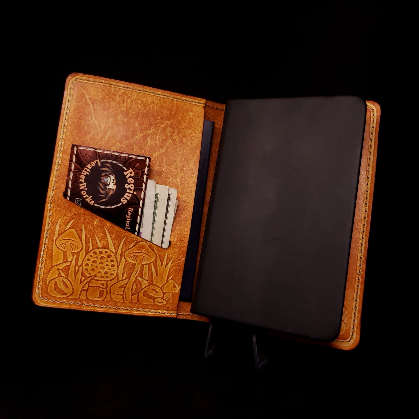 Brown leather notebook cover holding a pocket journal and embossed with a mushroom design.