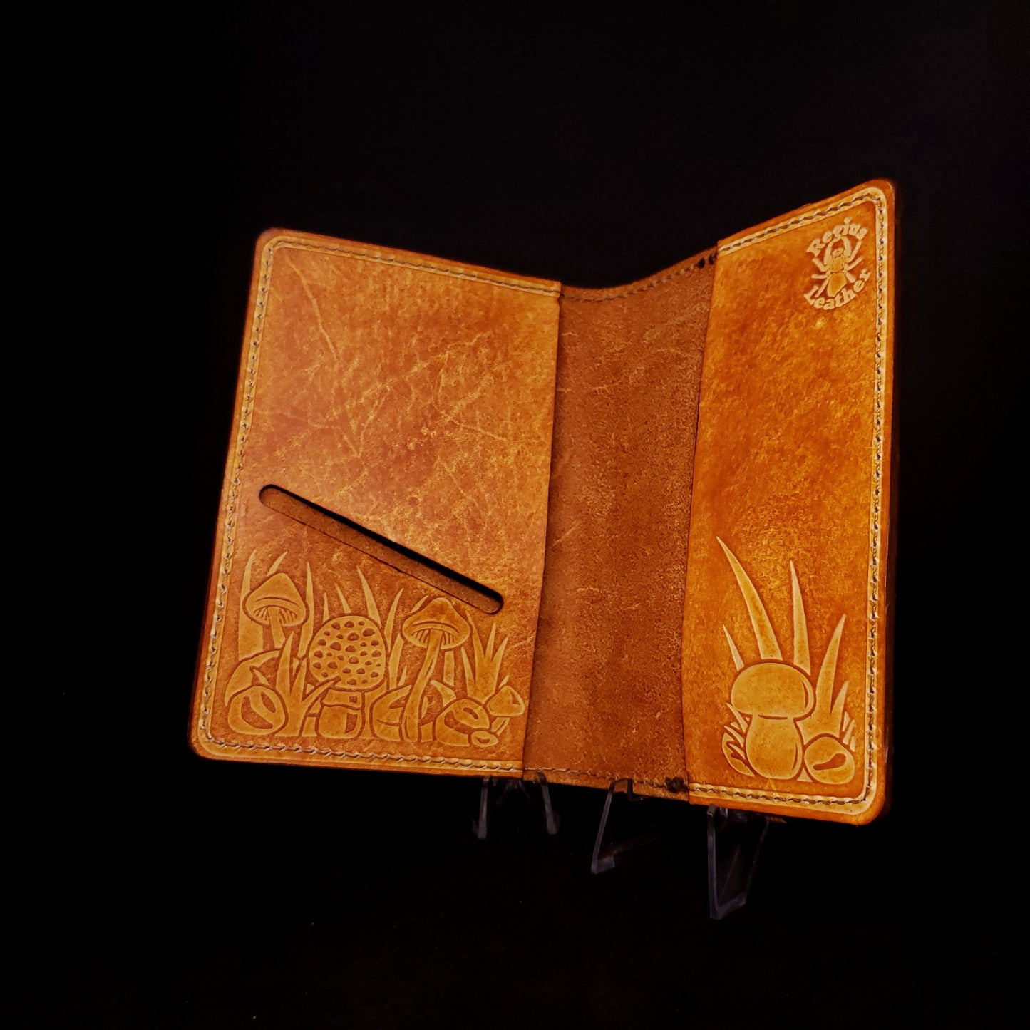 Brown leather notebook cover with a card slot and embossed with a mushroom design.