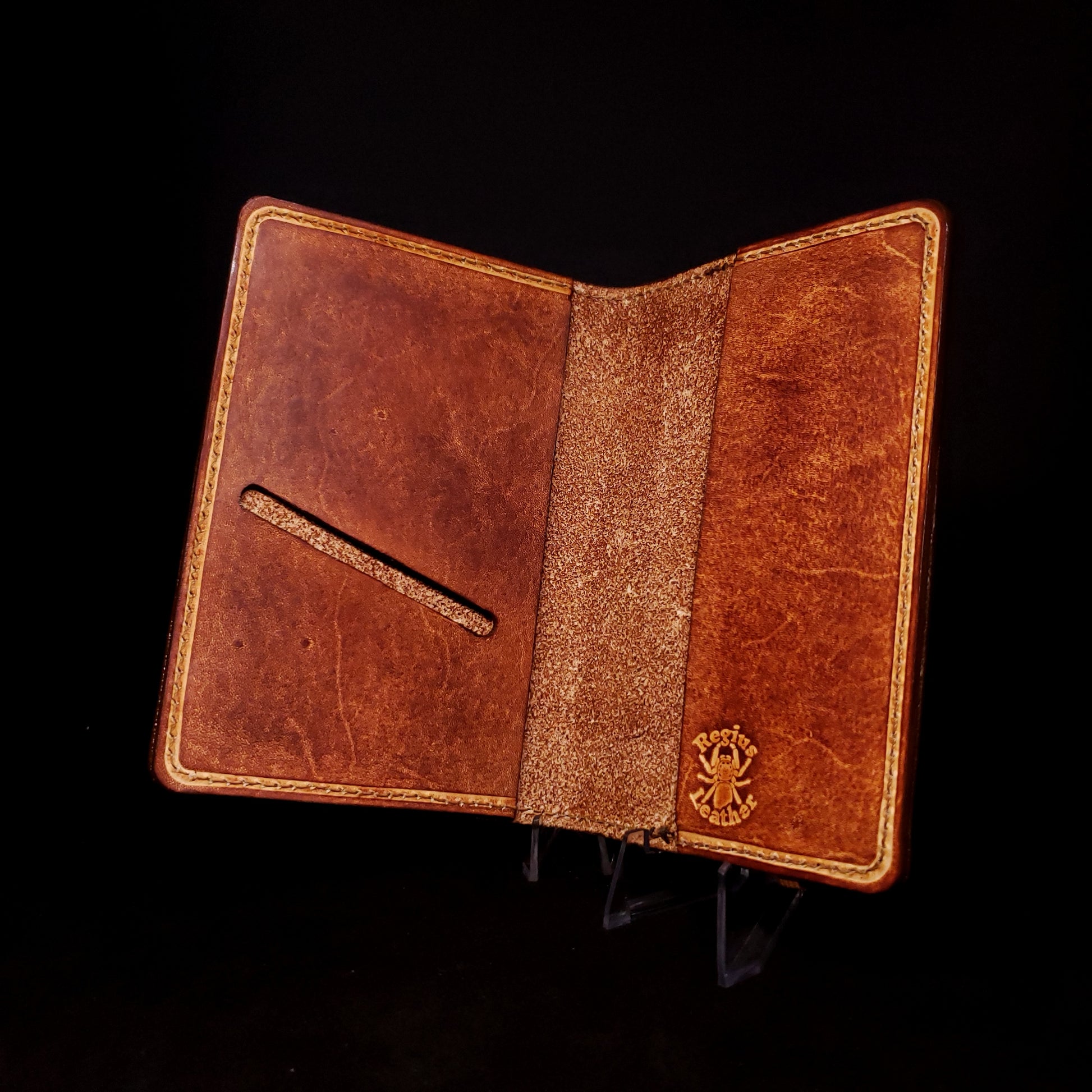 Brown leather notebook cover with a card slot on its left side and a Regius logo on its right sleeve.