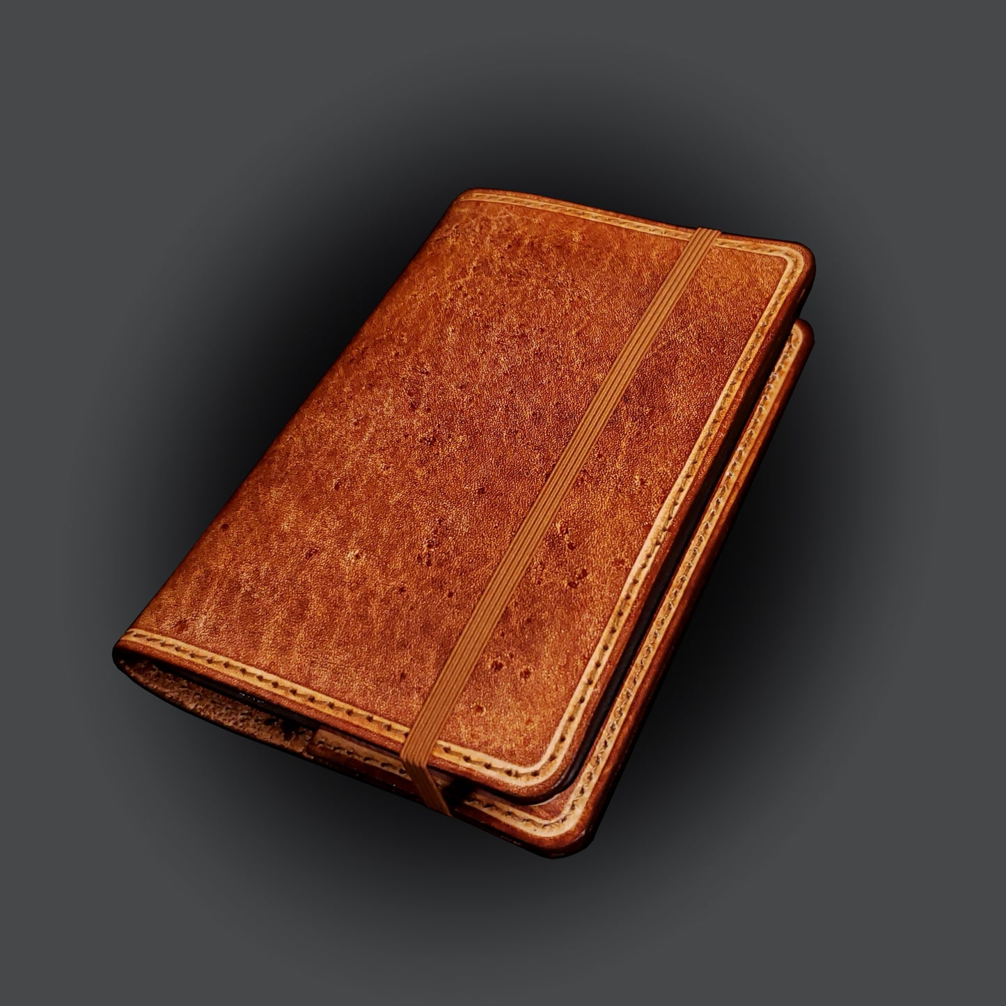 Brown leather notebook cover, closed with an elastic strap.