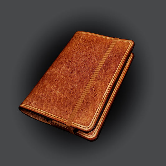 Brown leather notebook cover, closed with an elastic strap.