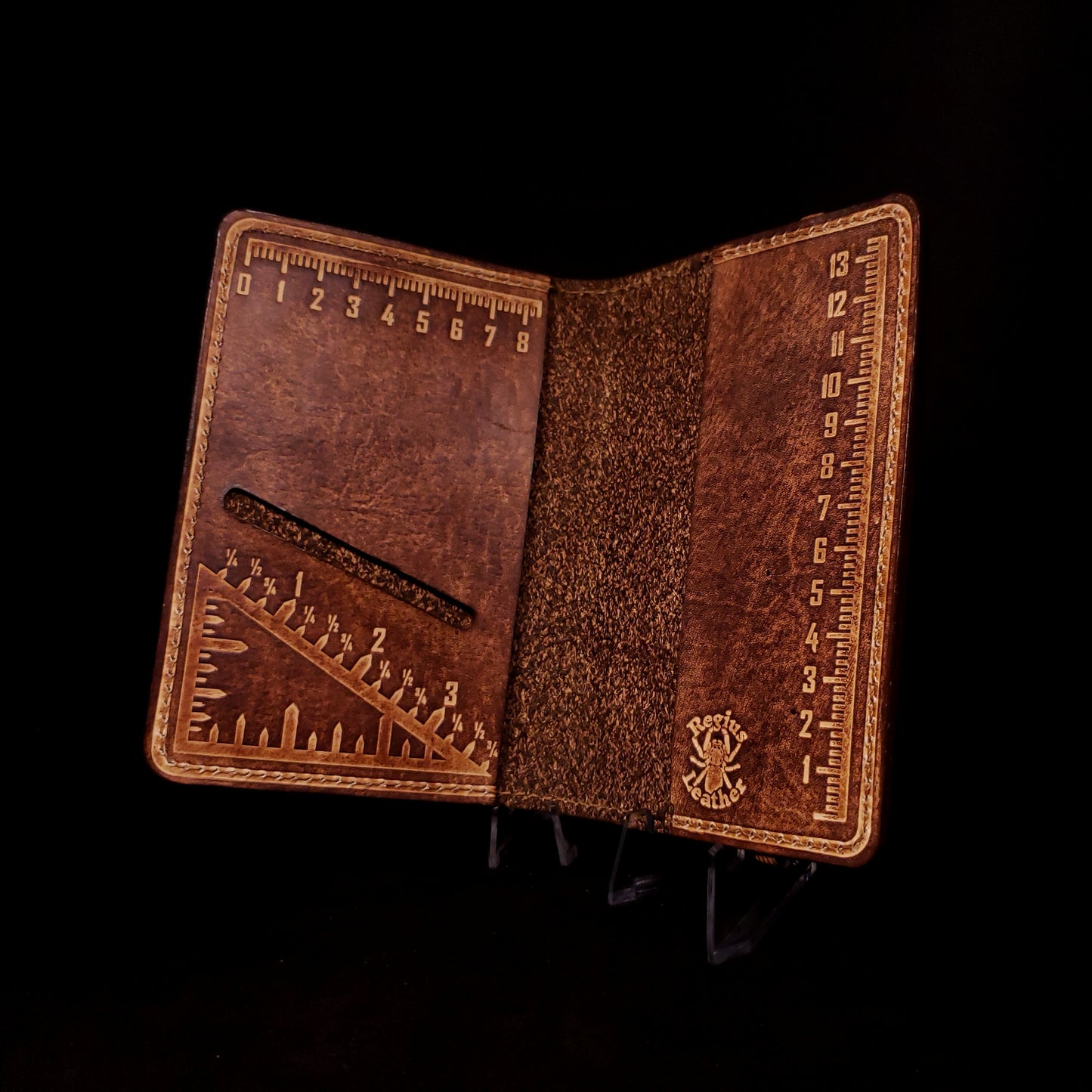 Brown leather notebook cover with a card slot and embossed with two metric rulers and an imperial triangle measuring square.