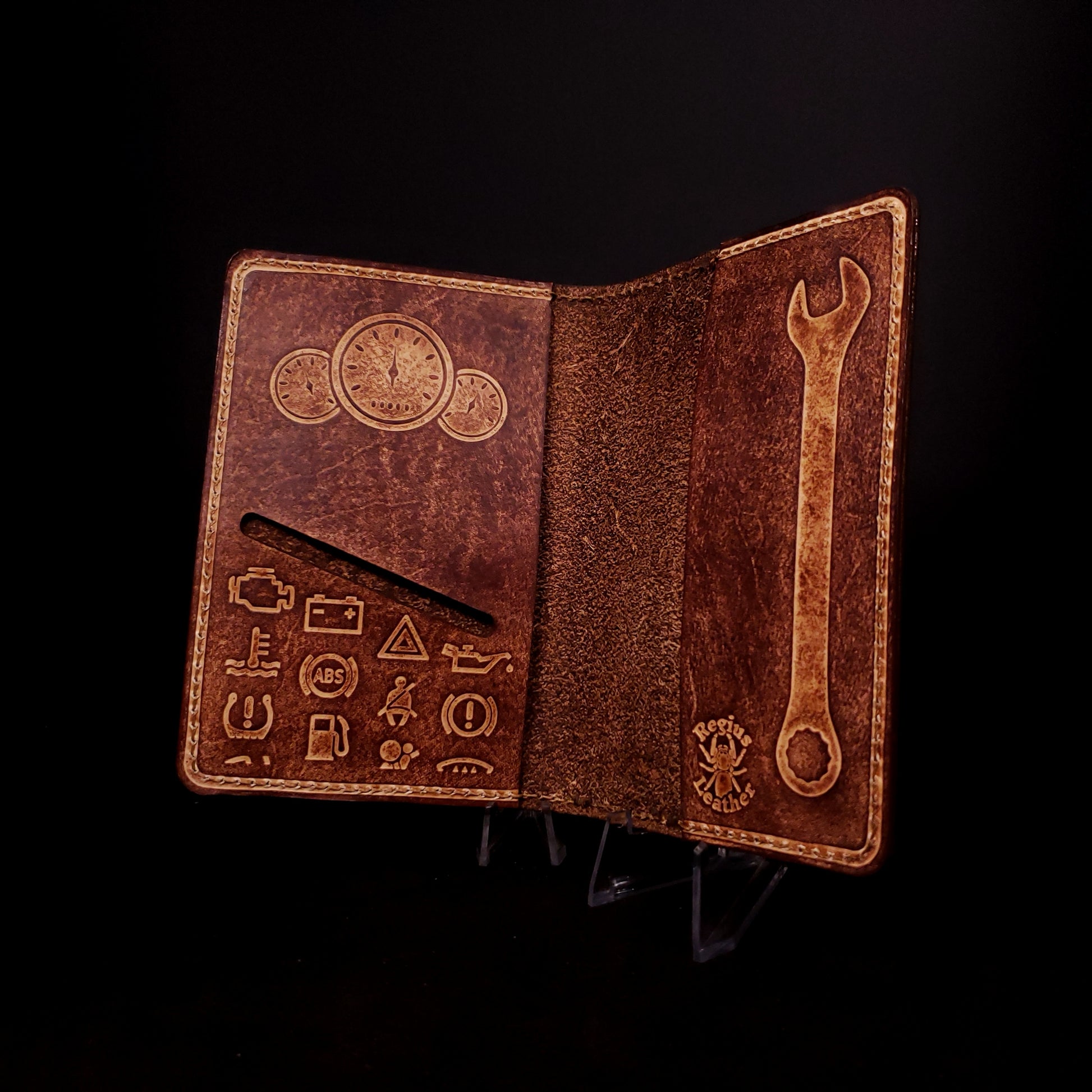 Brown leather notebook cover with a card slot and embossed with gauges, dash board warning lights, and a wrench.