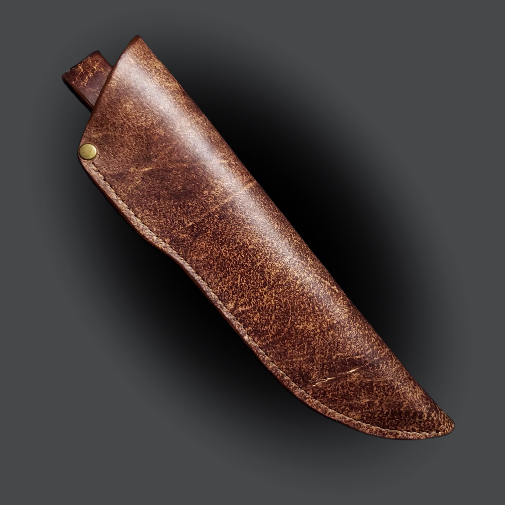 Brown leather knife sheath on a grey background.