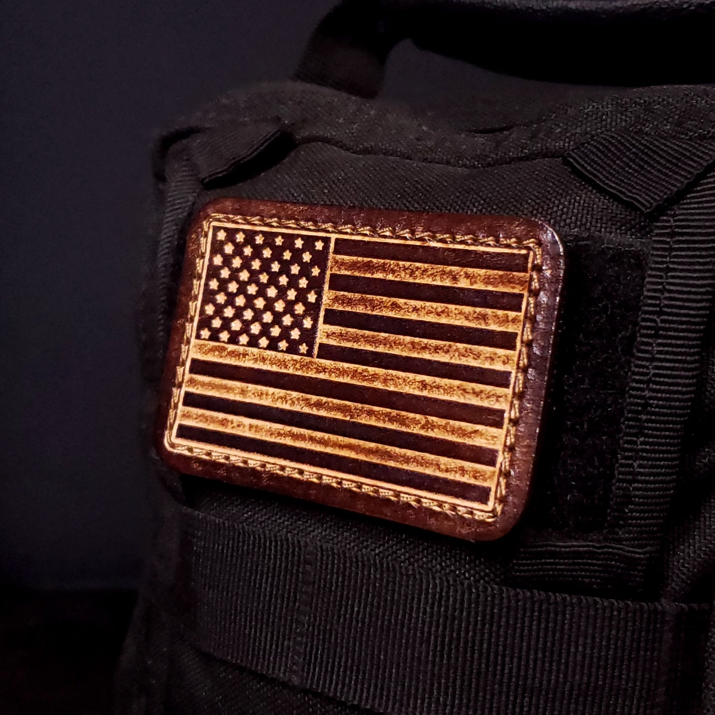 Brown rectangular velcro patch embossed with the American flag, affixed to a bag.