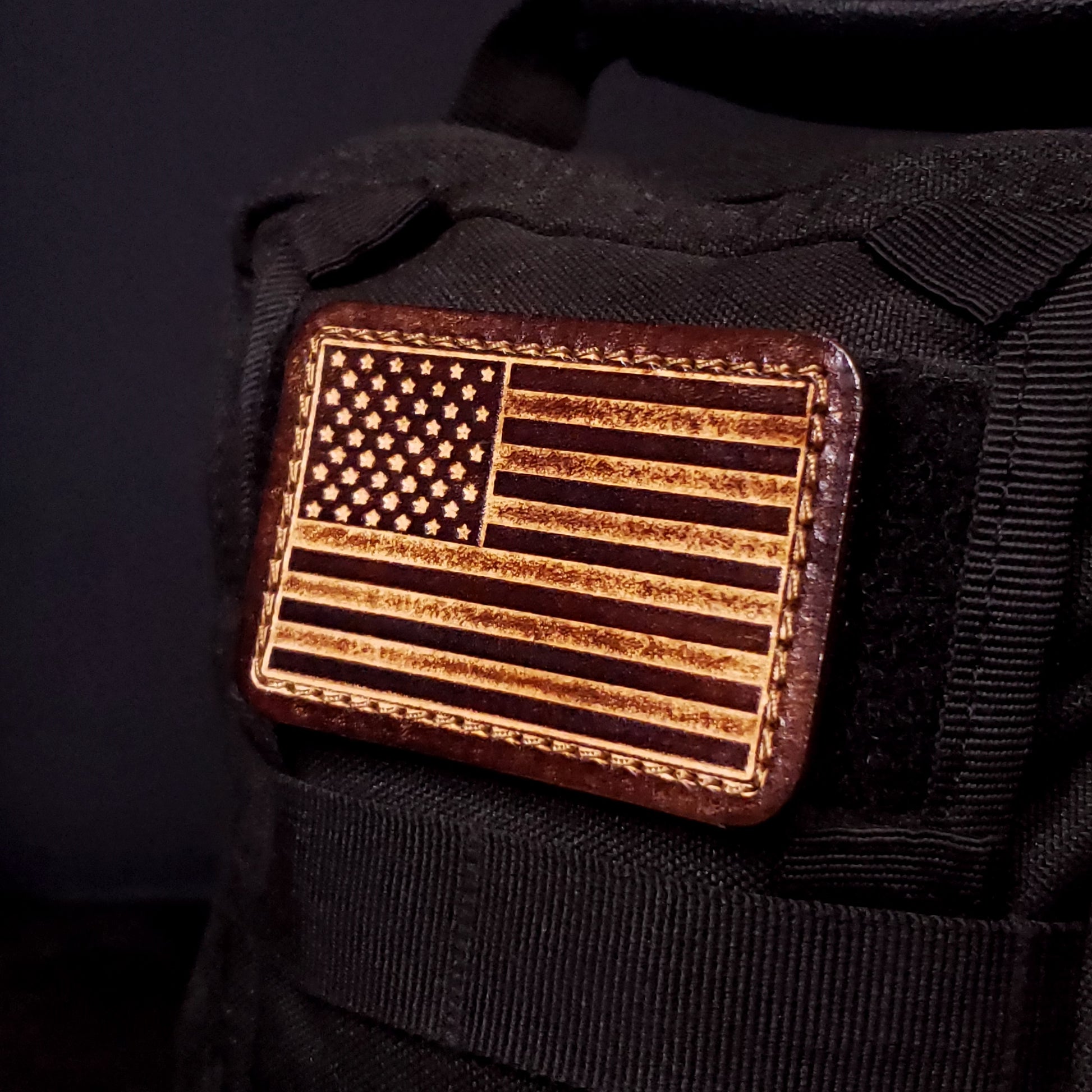 Brown rectangular velcro patch embossed with the American flag, affixed to a bag.
