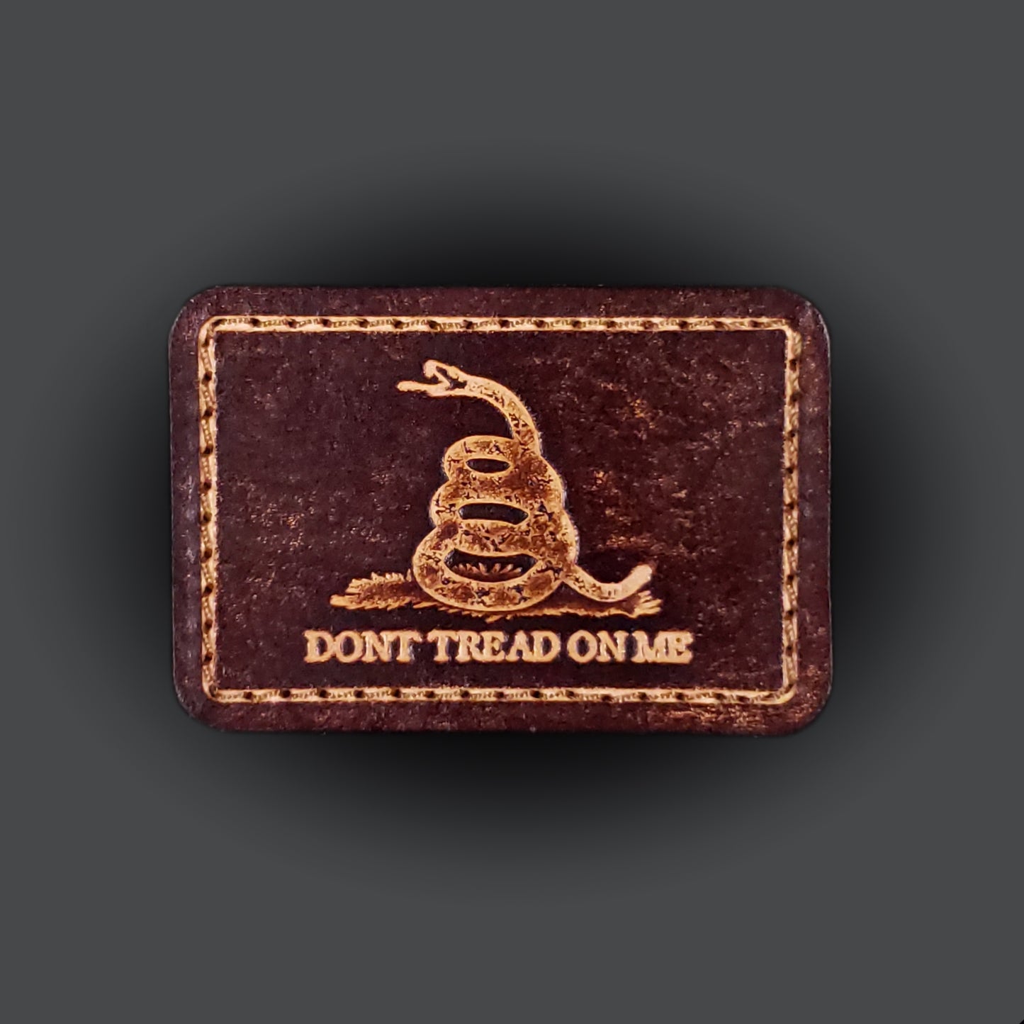Brown rectangular velcro patch embossed with a snake graphic and text that says "Don't tread on me".