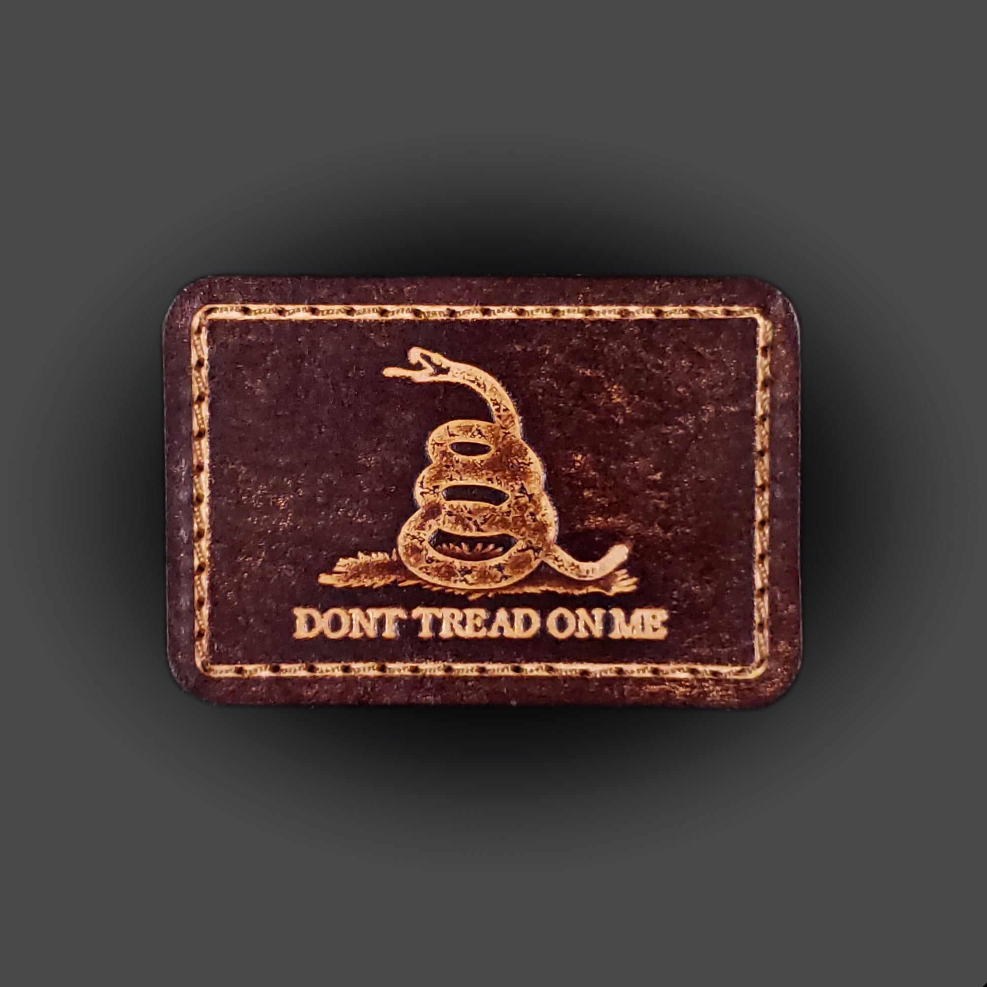 Brown rectangular velcro patch embossed with a snake graphic and text that says "Don't tread on me".
