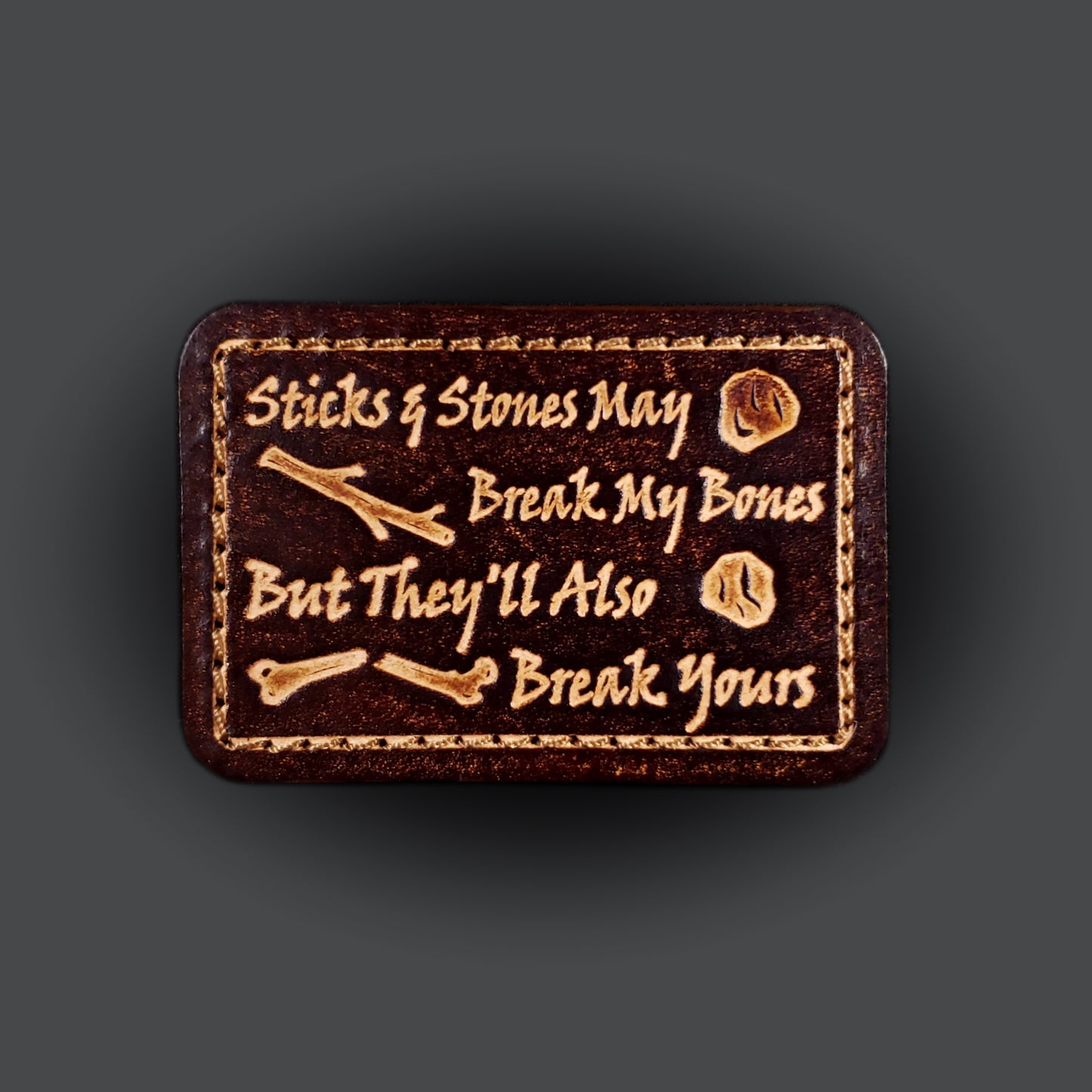 Brown rectangular velcro patch embossed with text that says "Sticks and stones may break my bones but they'll also break yours"