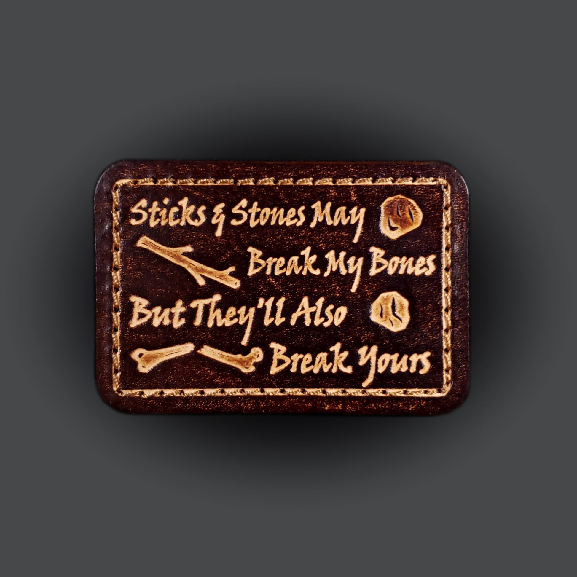 Brown rectangular velcro patch embossed with text that says "Sticks and stones may break my bones but they'll also break yours"