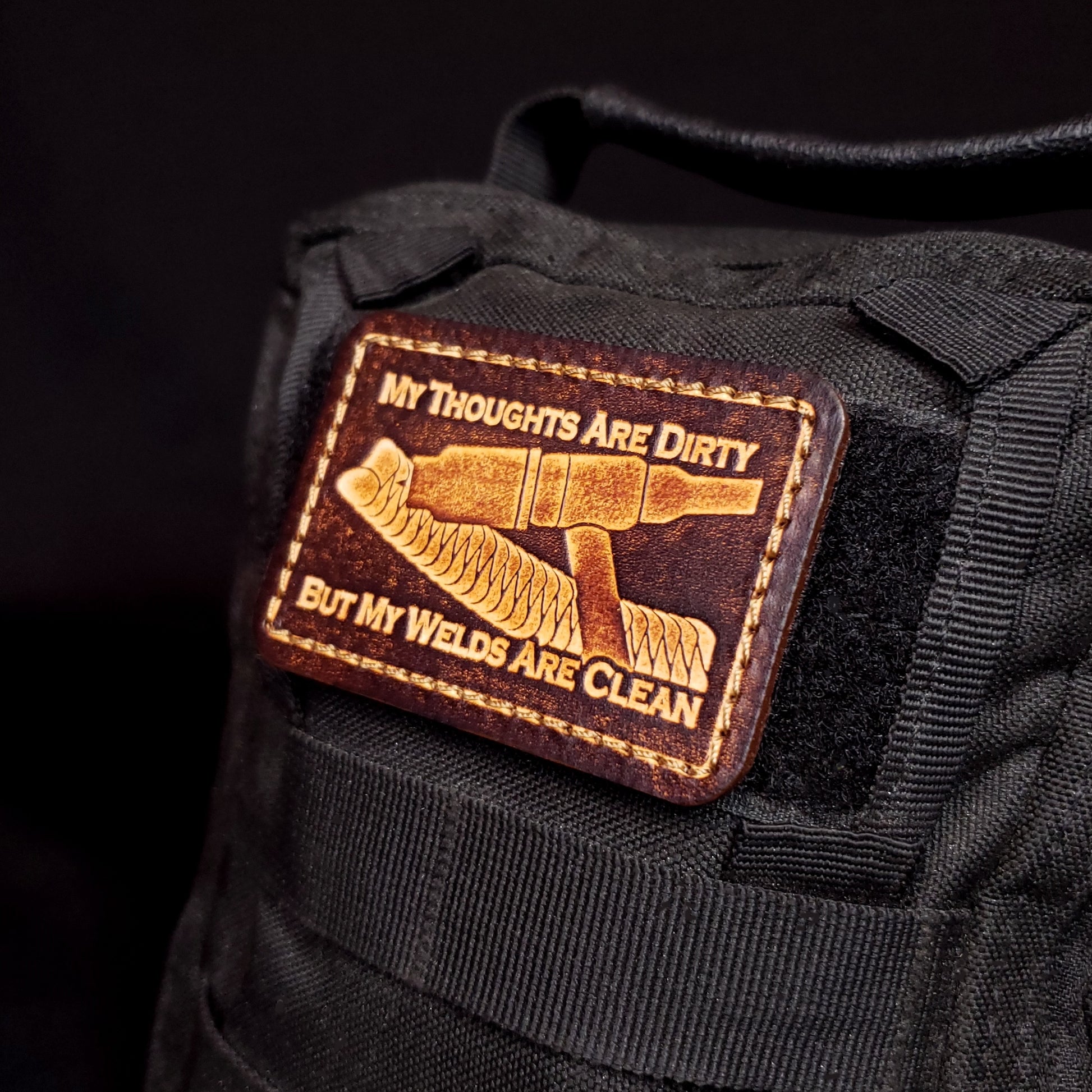 Brown rectangular velcro patch embossed with a picture of a welding tig torch and text, affixed to a bag.