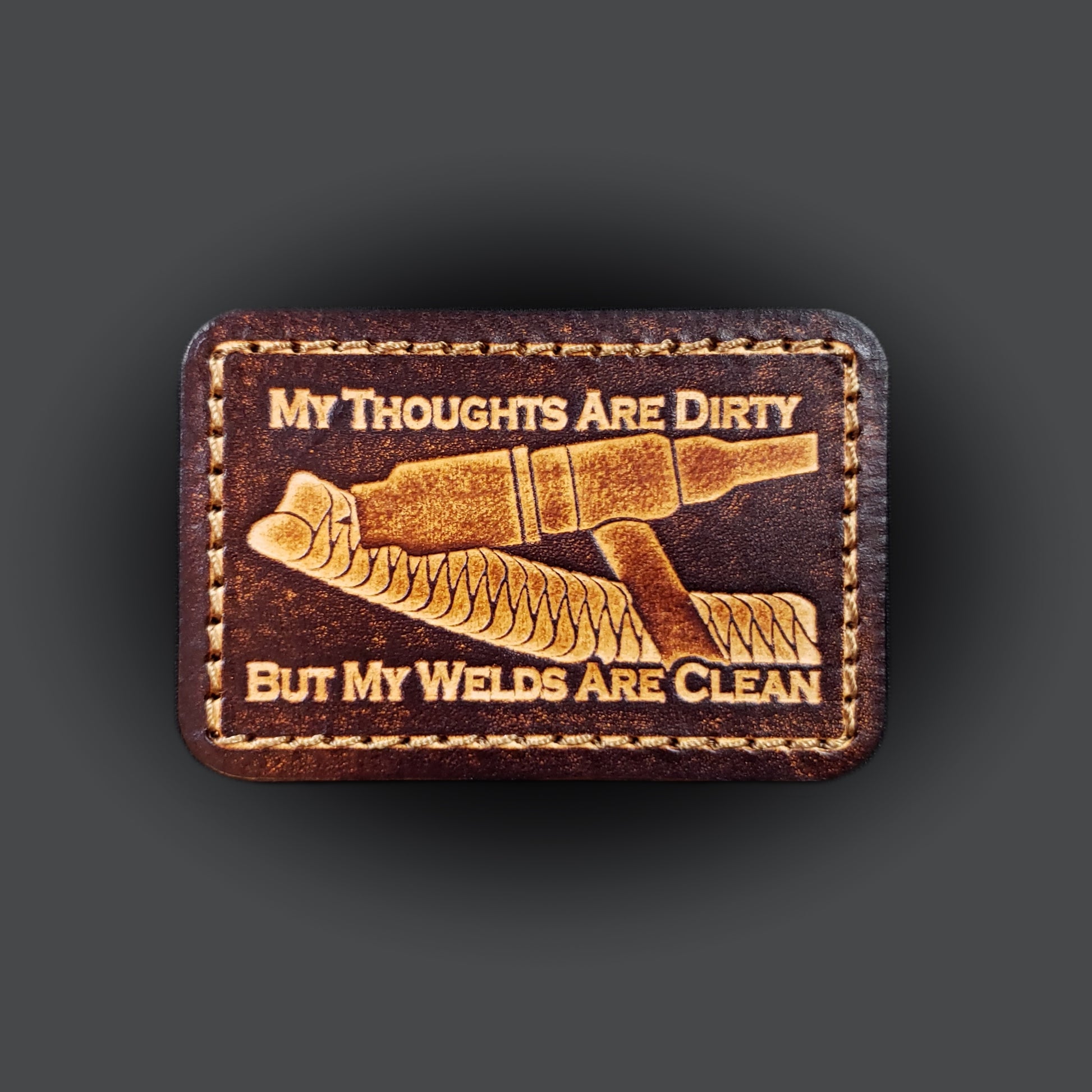 Brown rectangular velcro patch embossed with a picture of a welding tig torch and text that says "My thoughts are dirty, but my welds are clean".