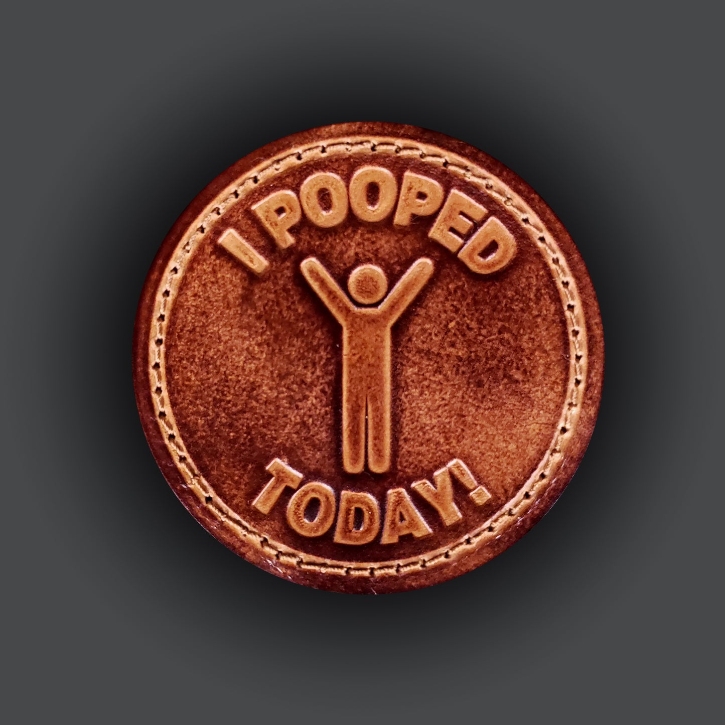 Brown leather velcro patch embossed with text that says "I pooped today", and a graphic of a cheerful person.