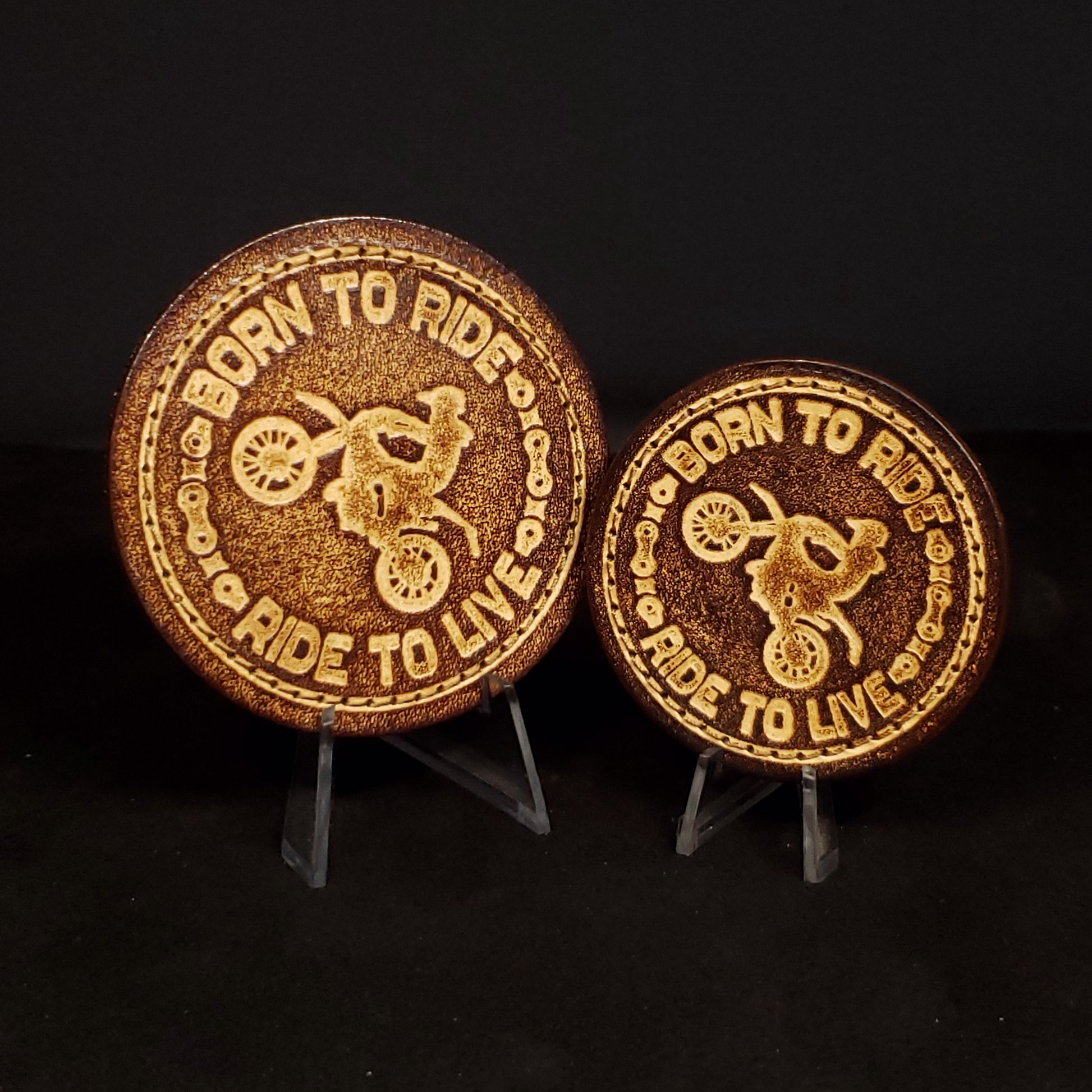 Two brown circular velcro patches embossed with text and a graphic of a motorcyclist doing a wheelie.